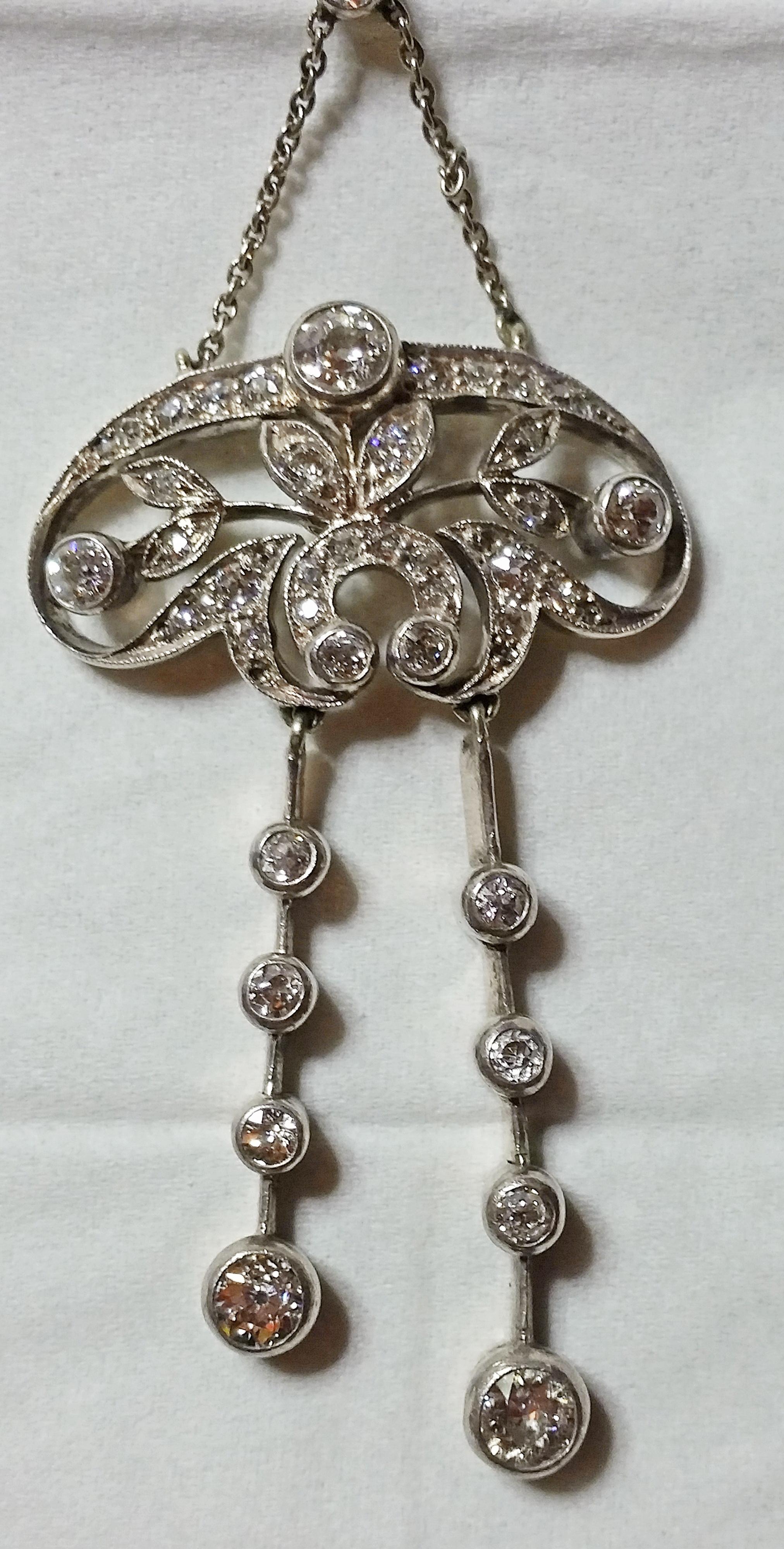 Golden Art Nouveau necklace of finest appearance, looking like stylized flower's blossoms attached to leafy stems - these ones edged by oval frame covered with diamonds.  Additionally, there are two pendants attached to frame which are decorated