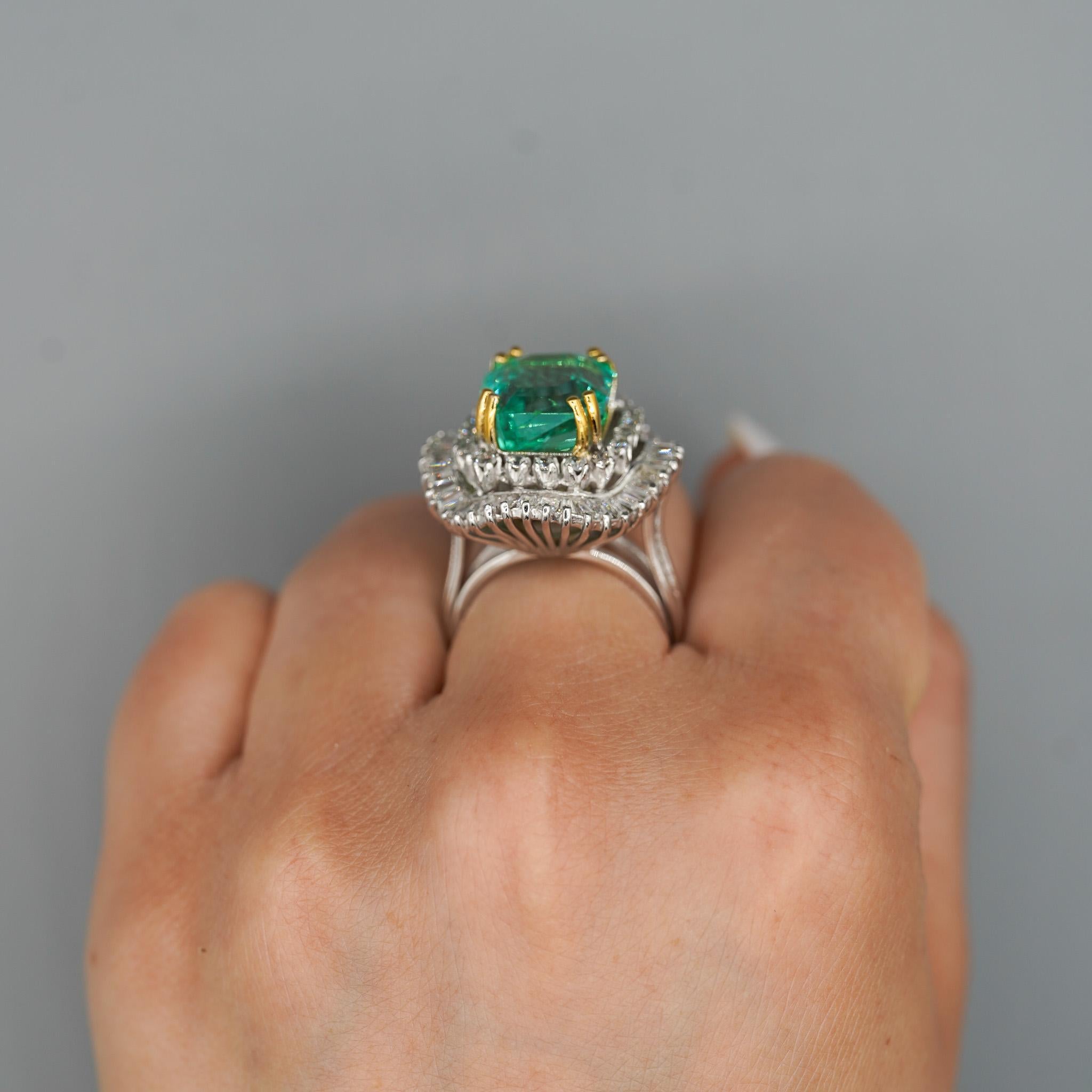 Questo incredibile anello in stile ballerina presenta un vivido smeraldo da 9,17 carati proveniente dalla miniera di Chivor, incorniciato da 3 carati di diamanti a taglio transitorio in un'intricata doppia aureola. Un audace design vintage
