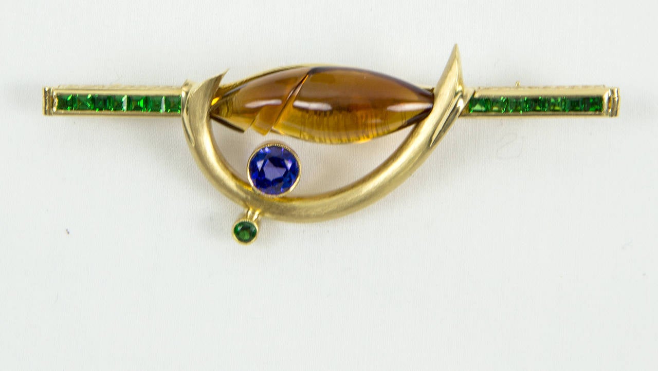 Dynamic Somos Abstract Pin; hand crafted in 18K Yellow Gold set with Citrine Tsavorite Garnet Sapphire; citrine signed by Munsteiner,  precious gems cutter; Pin Designer signed: Somos 18K. Approx. size:  67mm long x 20mm wide and the Citrine is