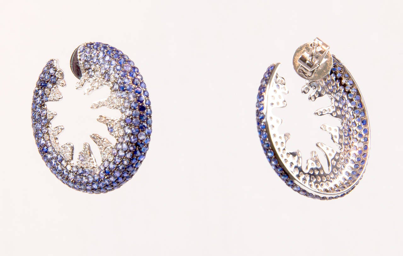 Iconic Diamond and Blue Sapphire Creole-style Hoop Earrings, encrusted with a total of 120 micro-set round brilliant-cut diamonds and a total of 400 round-cut blue sapphires; post backs, mounted in 18k white gold; Dimensions: 30mm diameter. The