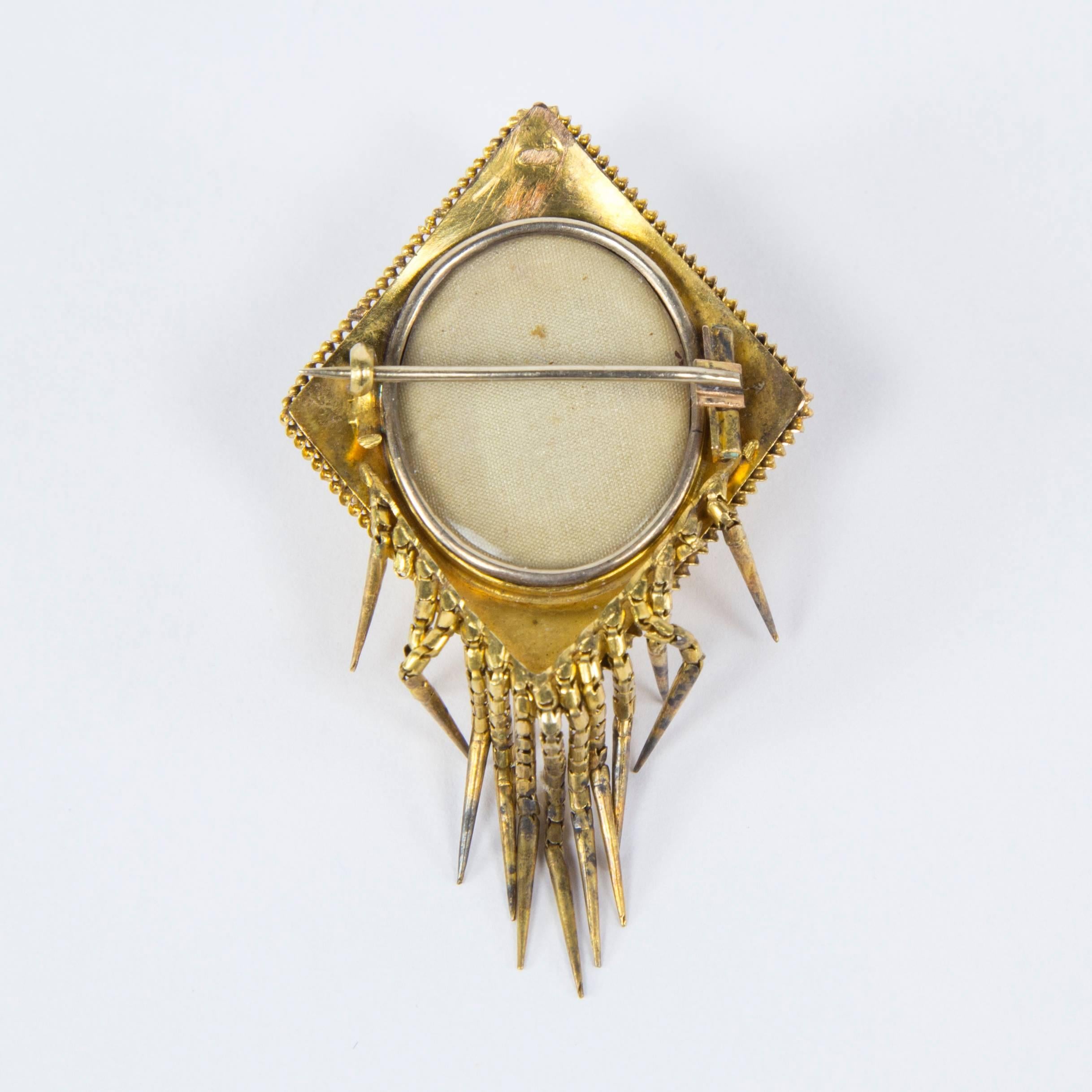 Victorian Diamond shaped Gold Mourning Brooch with hanging articulated gold tassels; beautifully hand crafted in relief; raised center featuring floral leaf designs; the reverse side has a place for a photo; approx. size: 2” x 1.5”. (tests to 14k