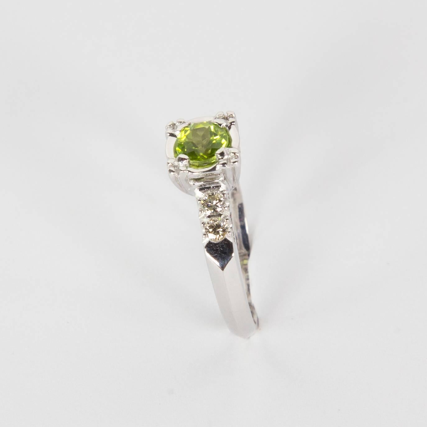 Belle bague de fiançailles solitaire centrée sur une tourmaline verte d'environ 0,45 carat, rehaussée de deux diamants sur chaque épaule de la monture en platine. Taille de l'anneau : 5,5 ; possibilité de redimensionnement gratuit de l'anneau. Une