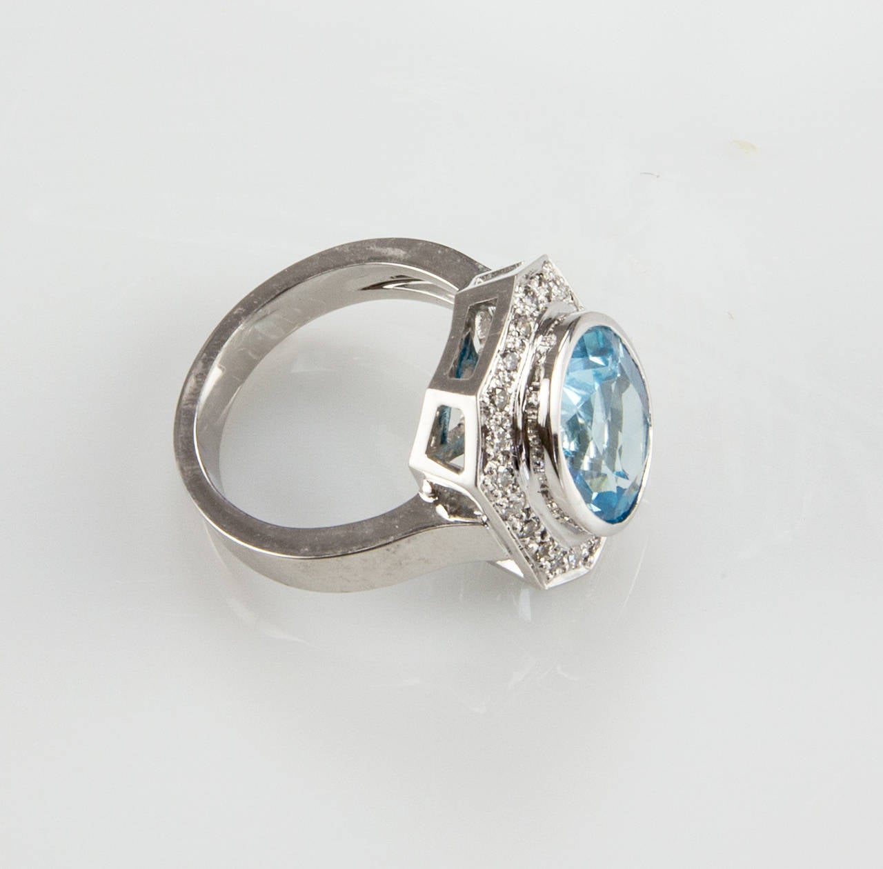 Centering an Oval 8.10 Carat Blue Topaz surrounded by twenty-four round cut diamonds; approx .24tctw; beautifully hand crafted in 18k white gold mounting; Ring size: 7.25. We offer complimentary ring re-sizing. (14mm x 12mm x 6.5mm). A Chic and Show