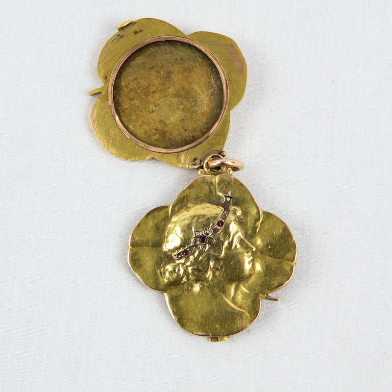 Beautiful Art Nouveau Slide Locket Pendant, in the form of a clover leaf, embossed woman's profile, enhanced with simulated rubies and simulated diamonds set into her headband. Handmade gilt rose metal. The locket measures 1.5” across and is capable
