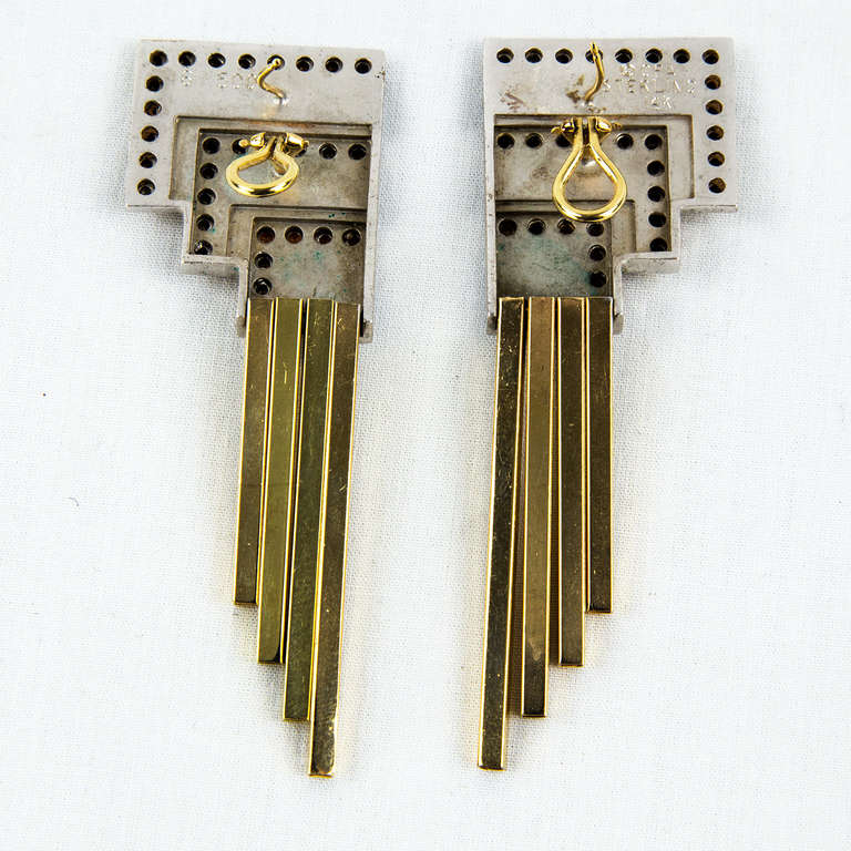 Dynamic Erte Gold and Silver Onyx Moderne Dangle Earrings signed: Erte; marked & numbered: 16/500 CFA STERLING 14k; measuring approx. 2.5” long.

The geometry of Moderne comes directly from the Art Deco period, with its emphasis on square and