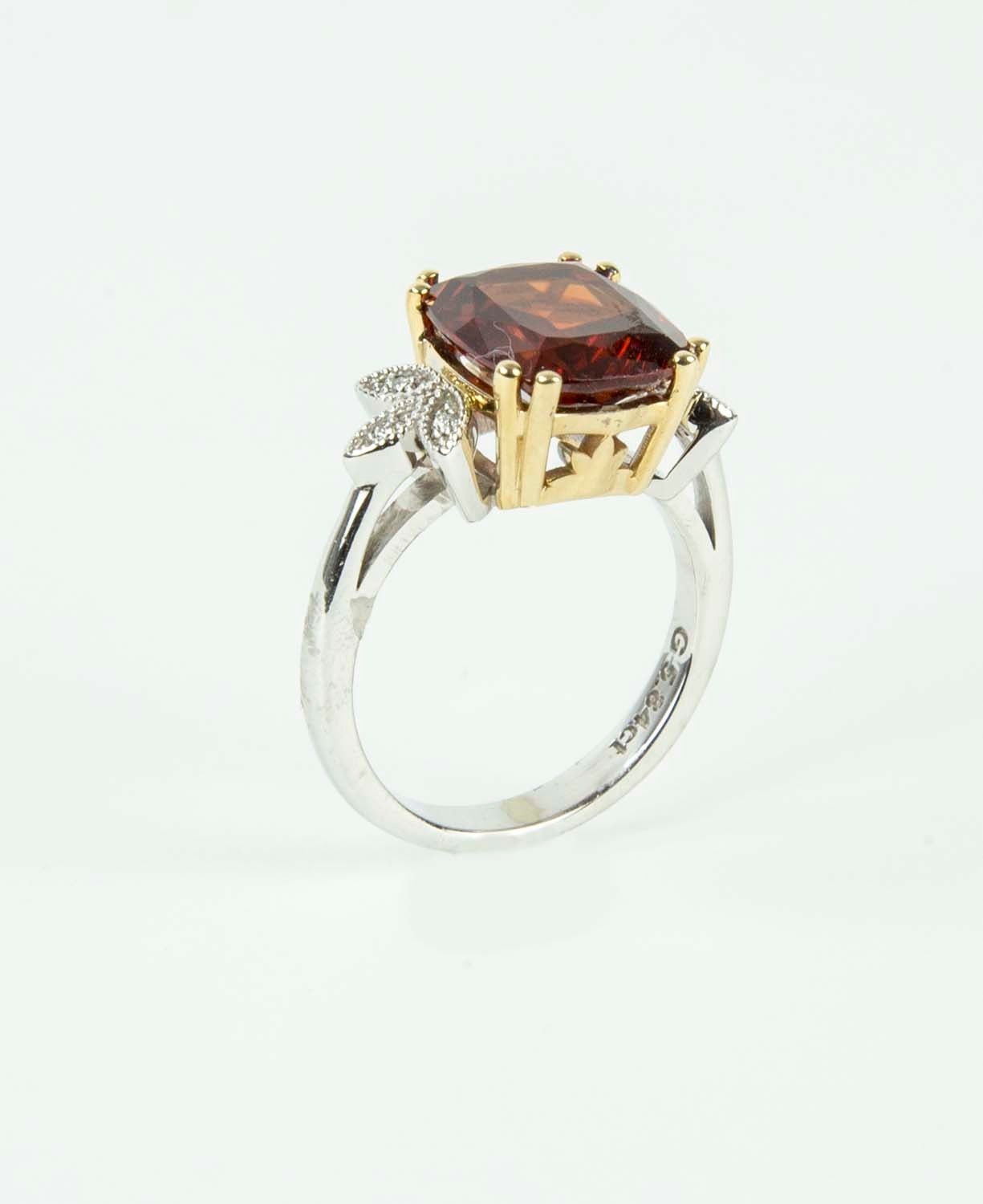 Centering a Beautiful 5.84ct Cushion-cut Spessartite Garnet flanked by six round brilliant cut diamonds, one on either side; approx .05tctw; hand crafted in 14k two tone white and yellow gold mounting; Ring size: 6.75. *Complimentary ring sizing