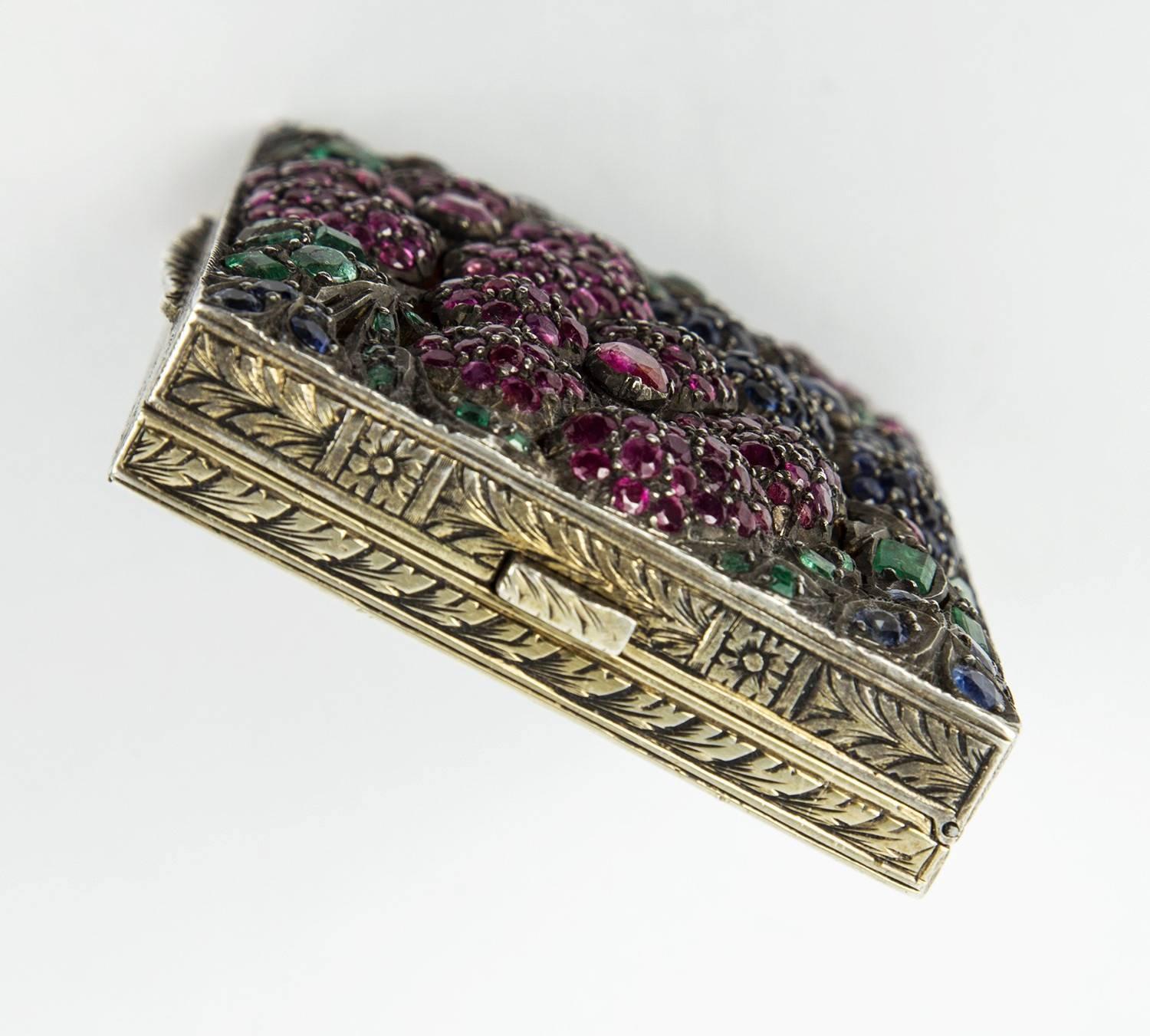 
Fabulous 1930s Heavily Set Precious Sapphire Emerald Ruby Silver Vanity Compact Box 
Beautiful Silver gem-set compact case, rectangular top features hand carved openwork florals, encrusted with Sapphire, Emerald and Ruby Blossoms; opens with