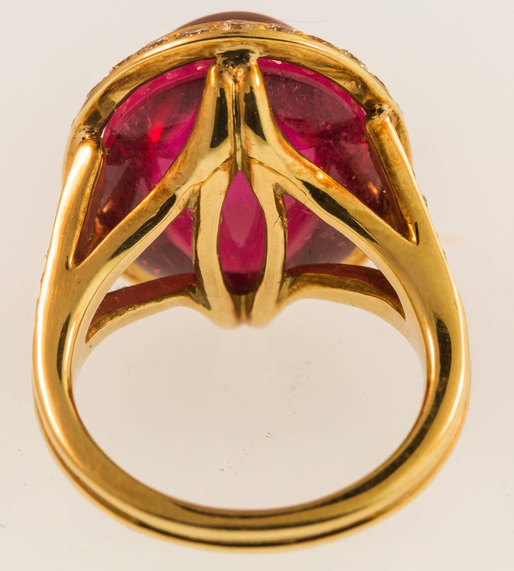 Centering a Beautiful 16.90ct oval Cabochon Rubellite from Brazil; measuring approx. 15.8 x 13.0mm surrounded by round brilliant cut diamonds, 0.96tctw; mounting in 18K yellow gold; Ring size: 6. Complimentary ring sizing available. Classic and