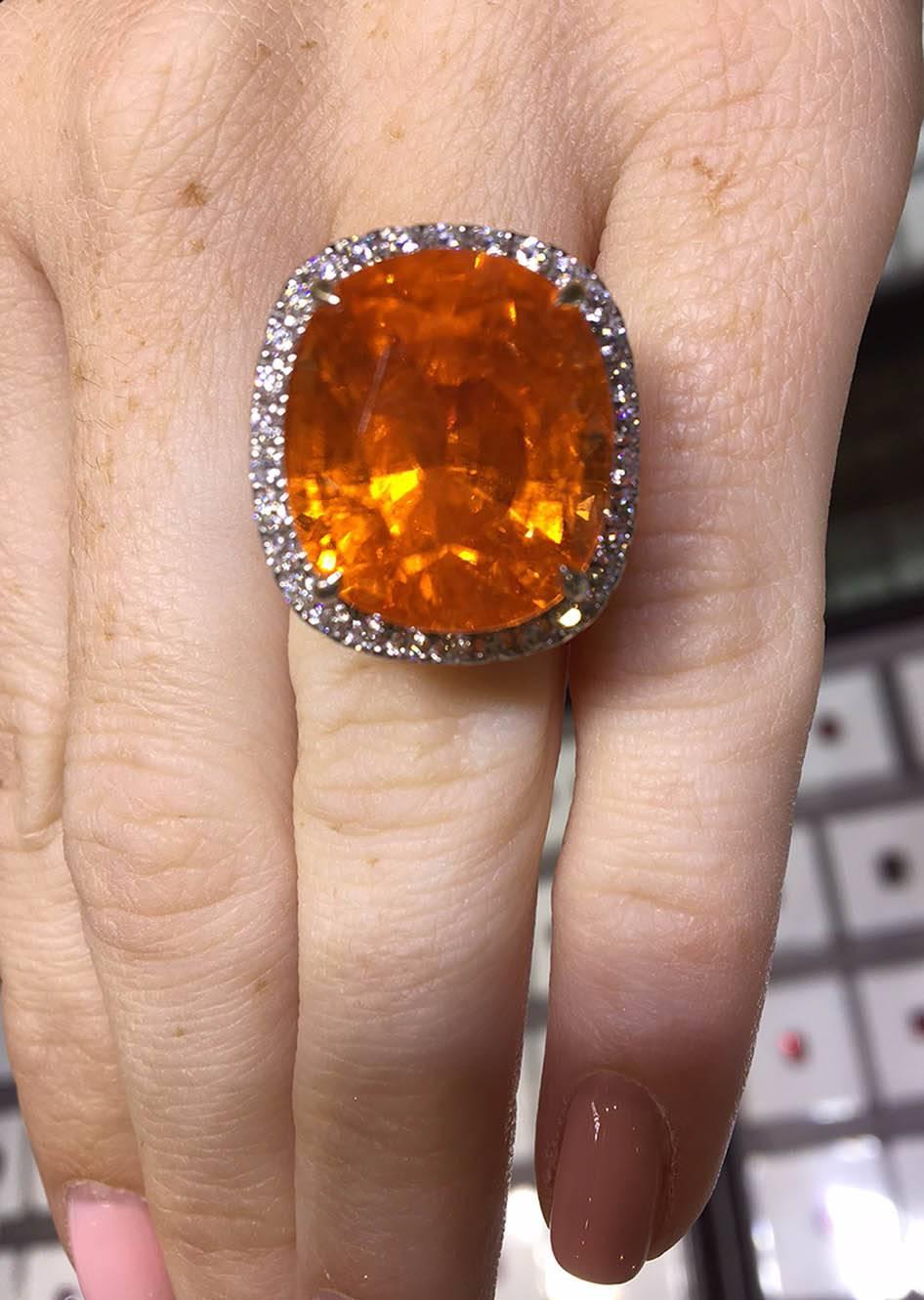Simply Beautiful! Centering a Beautiful 37.75 Carat Mandarin Garnet Cushion cut; measuring approx. 18.2mmx 15.8mm x 13.6 mm, surrounded by 54 Round Brilliant Cut Diamonds, 1.65tcw; G-H / VS-SI; 18K white gold mounting, prong set. Ring size: 6.