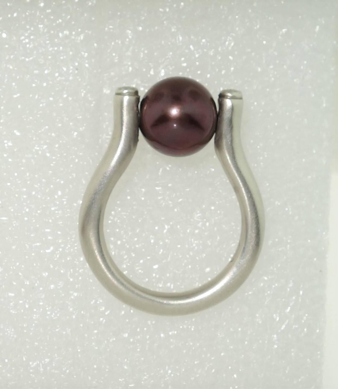 Beautiful ring featuring a 10mm Chinese  freshwater Chocolate Pearl held in center by a 14K pin; enhanced with diamonds, approx. .10tctw; satin finish Sterling Silver Tarnish-resistant Rhodium mounting; Size 7; We offer complimentary ring re-sizing.