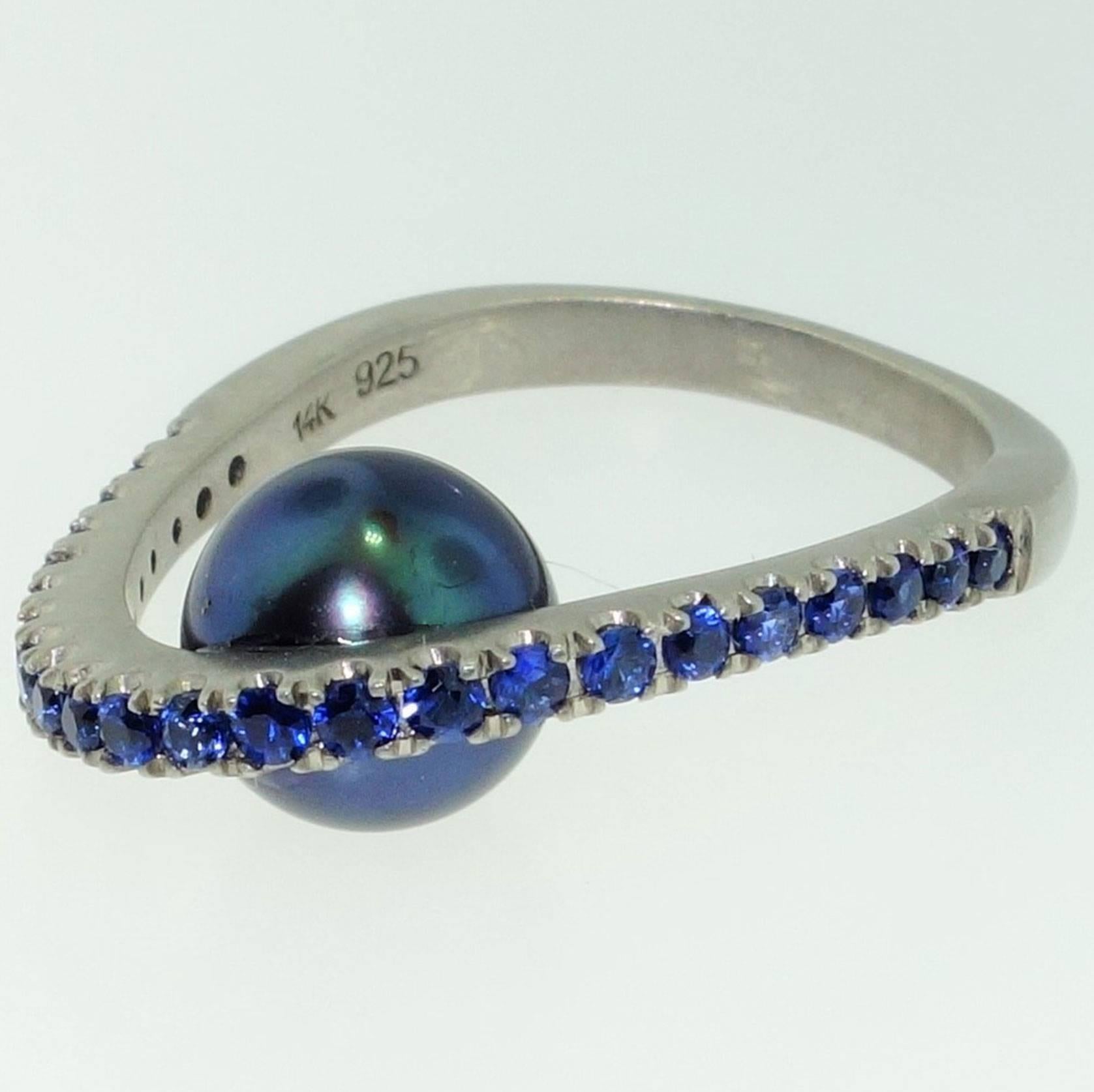 Featuring a Black freshwater pearl below; top of ring set with Blue Sapphires; approx. .70tctw; Sterling Silver Tarnish-resistant Rhodium mounting; Size 7; we offer complimentary ring re-sizing. More fabulous in person! A Striking Statement, Classic