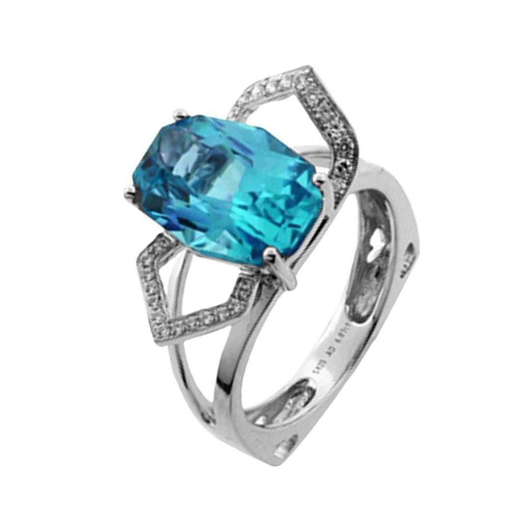 Impresionante anillo de Topacio Azul acentuado por veintiocho Diamantes redondos talla brillante, Crepúsculo, el Topacio Azul talla facetada mide aprox. 14mm x 10mm, peso aprox. 6,37ct; montado en oro blanco de 14k. Tamaño del anillo: 7+. Se ofrece