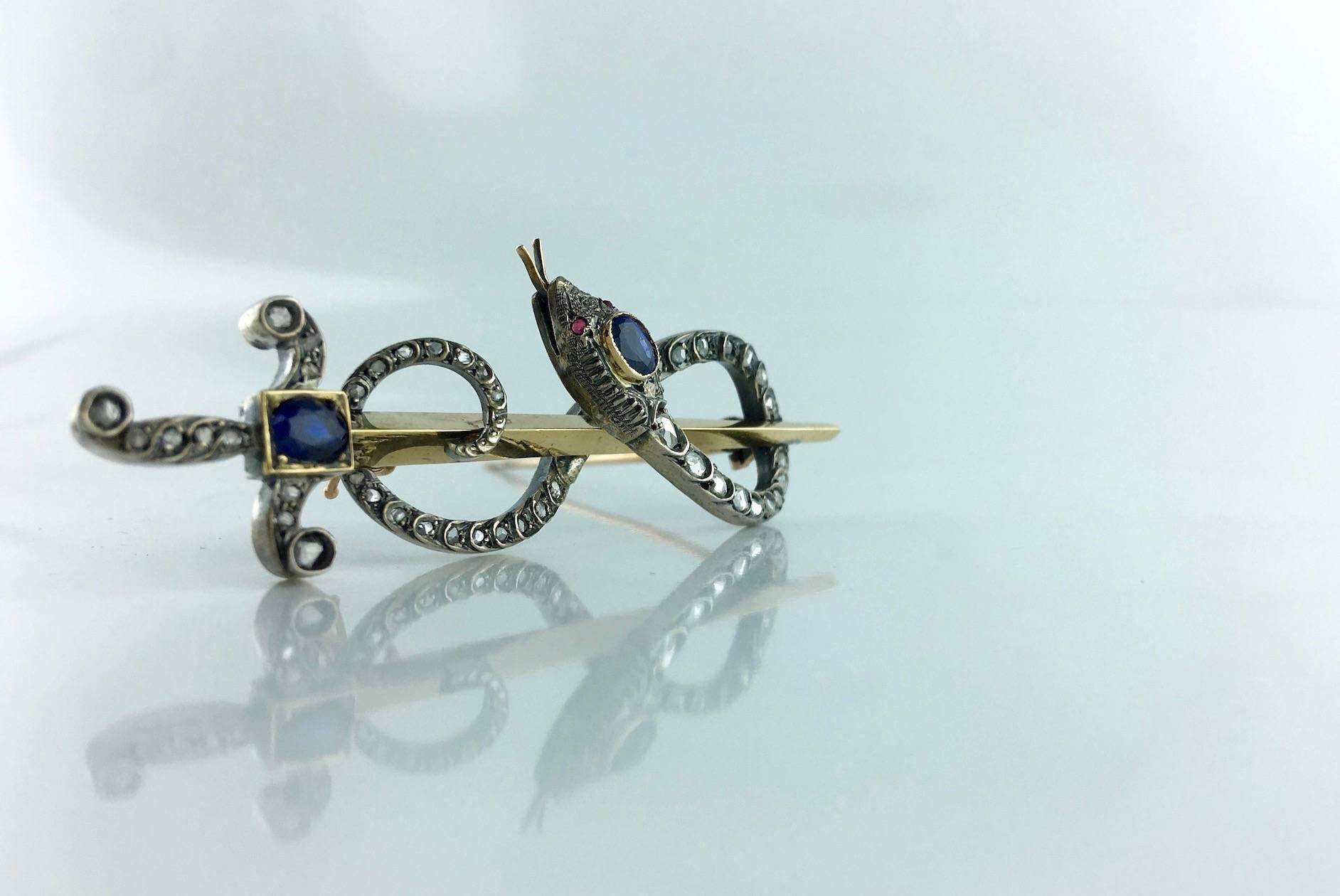 Amazing! This unique piece is literally a fantastic brooch. 
Antique Caduceus Arrow And Snake blue Sapphire and Rose-cut Diamond on Silver and Gold Brooch. Beautiful set reminded the snake's skin. Ruby eyes.
Late XIXth Century - Early XXth