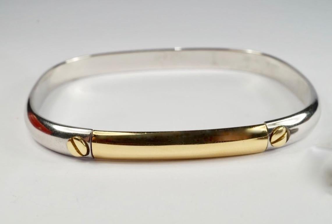 Cartier Bangle in yellow gold and steel. 
The curved rectangular bangle of bicoloured design, signed Cartier, numbered, inner diameter 5.8cm, accompanied by screwdriver and maker's case.
Circa 1982.