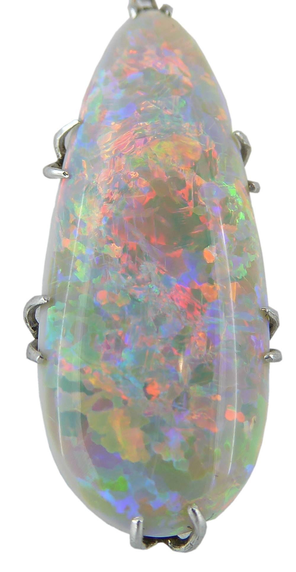 An opal and diamond centrepiece necklet consisting of a pear shaped, cabochon cut, white opal with exceptional blue/gree/orange play of colour and a red pin fire and rolling flash.  The opal is held in four split claw settings  and suspends from an