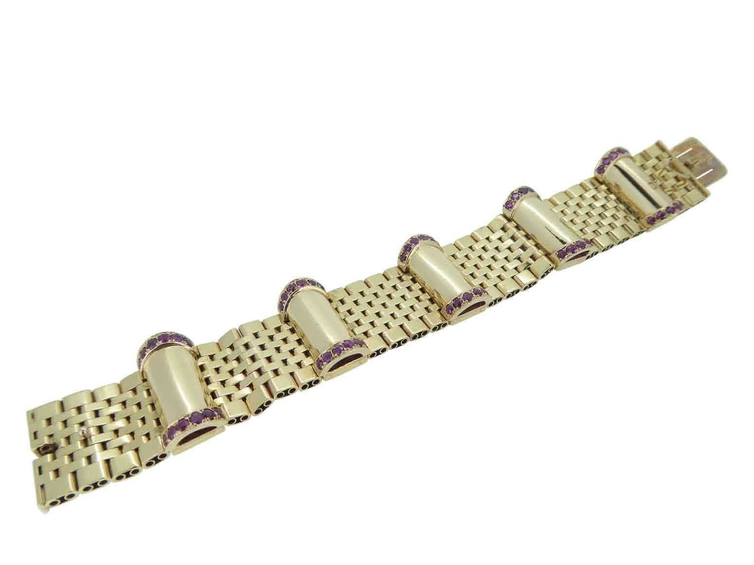 Stunning yellow gold bracelet comprising five sections of polished gold links laid in a brick fashion.  Each section is separated by semi-circular domed tubular links, the ends of which are studded with a row of rubies.  Fastens by a V spring catch