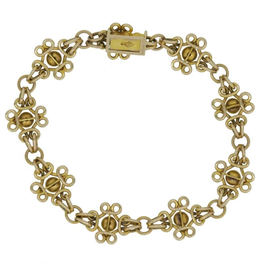 Late Victorian/early Edwardian era bracelet marked 15ct comprising nine decorative panels with a domed plain polished centre and looped wire surround.  These panels are connected to a round gold link by pairs of oval links to each side.  The