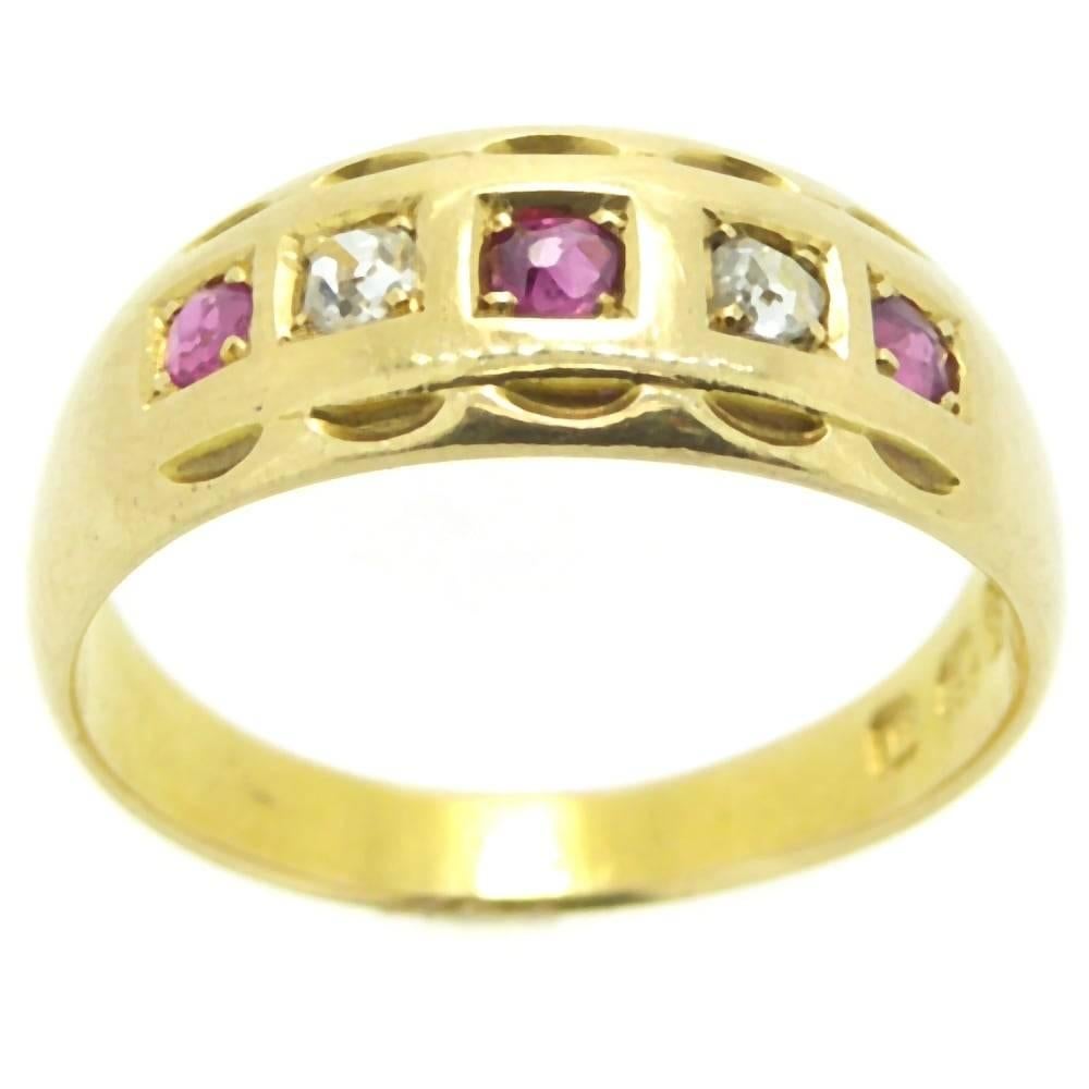 An antique ring from the English Victorian era boasting three rubies alternating with a diamond in a row across the top of a flat gold band edged with a fancy crimped design.  Hallmarked at the Birminghan Assay Office in 1887, the ring also displays