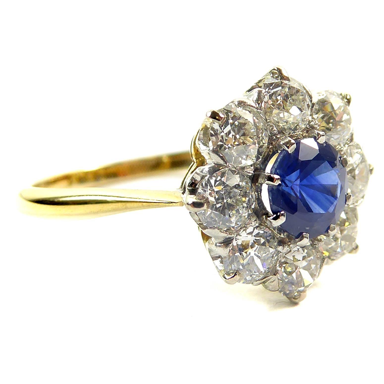 The ever-popular combination of sapphire and diamonds in a cluster design ring.  Always in demand as an engagement or dress ring, this example features a lovely royal blue sapphire in claw settings to a surround of diamonds.  The band is a