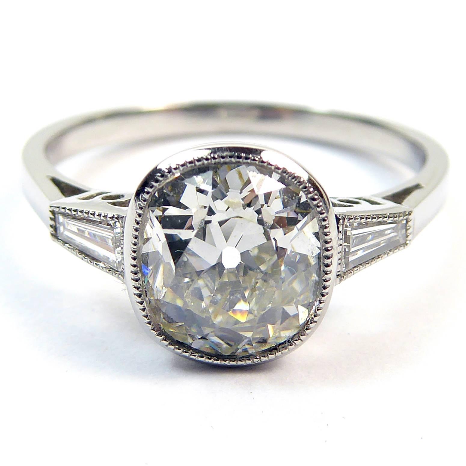 If a diamond can ever be described as discreet then the cushion-cut is it.   Just a shade different from the usual round brilliant cut, the curvacious shape sits beautifully within this rub over setting with its grain decoration and is typical of