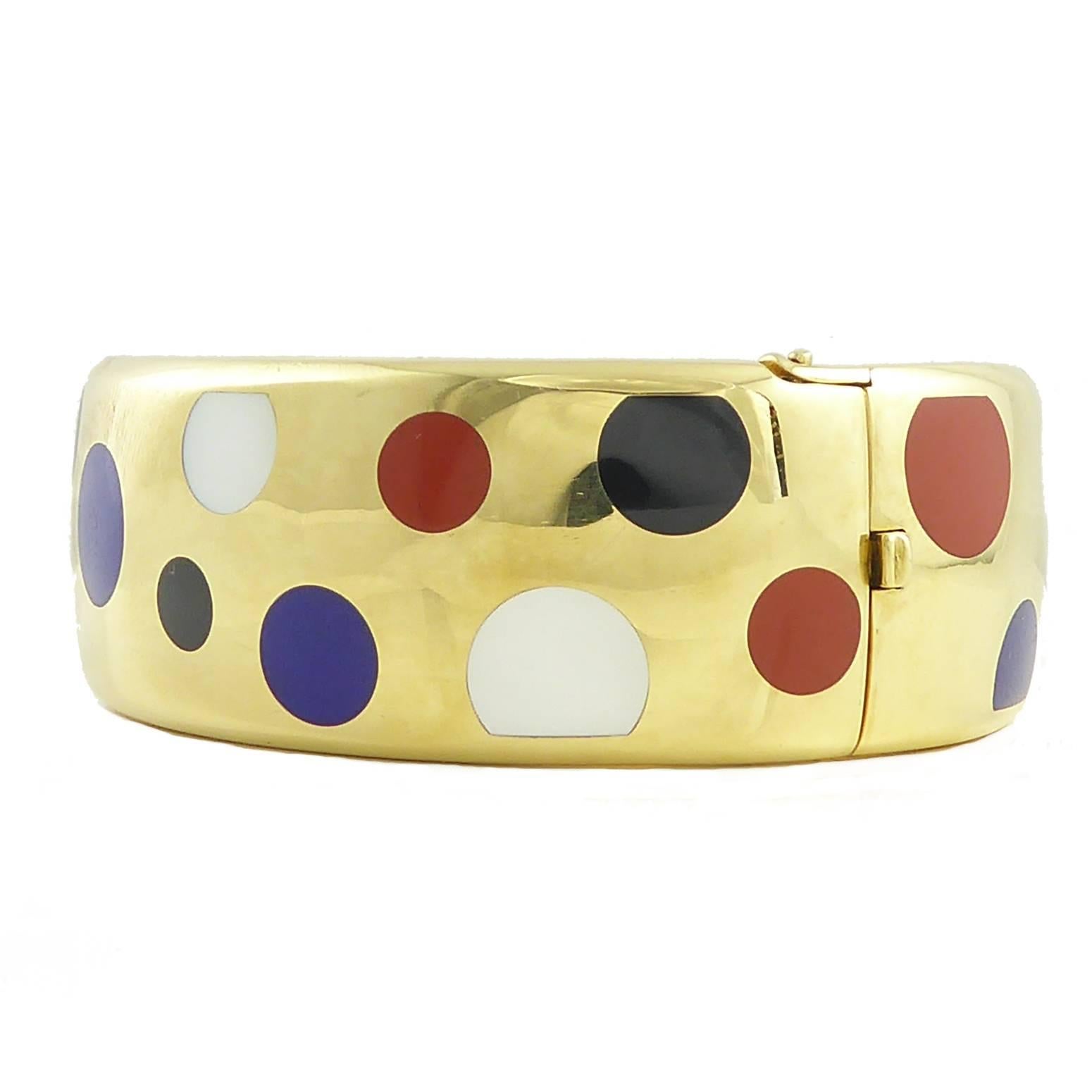 A glorious 18ct gold bangle by the celebrated Tiffany designer, Angela Cummings, inlaid with spots and dots of mother of pearl, lapis lazuli, onyx, and jasper.  The semi-precious gemstones are scattered randomy over a slightly domed bangle approx.