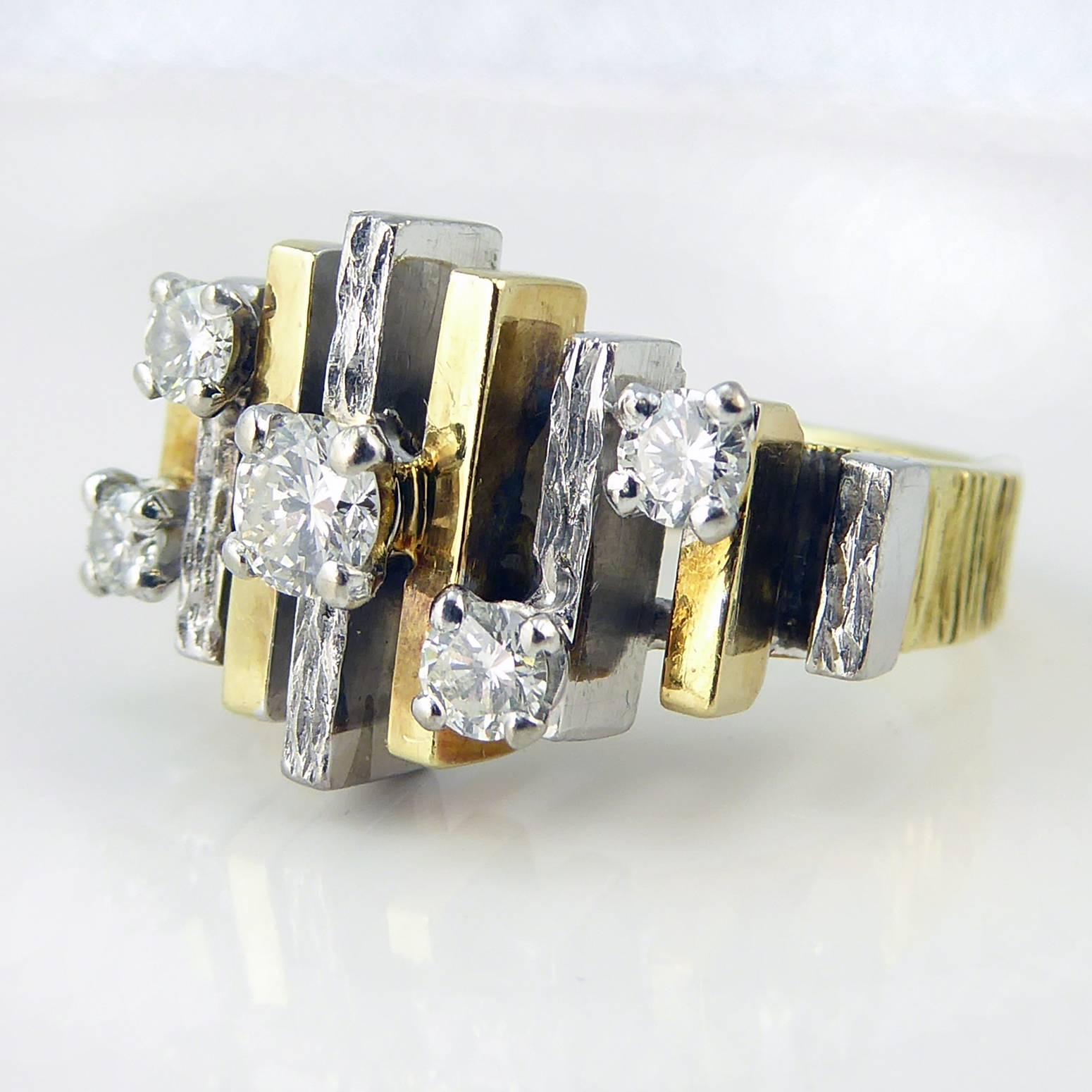 A fabulously architectural ring somewhat reminiscent of the brutalist style of architecture that lasted from the 1950s through to the middle of the 1970s. 

Alternating yellow and white gold bars sit on an open mount and graduate down in size from