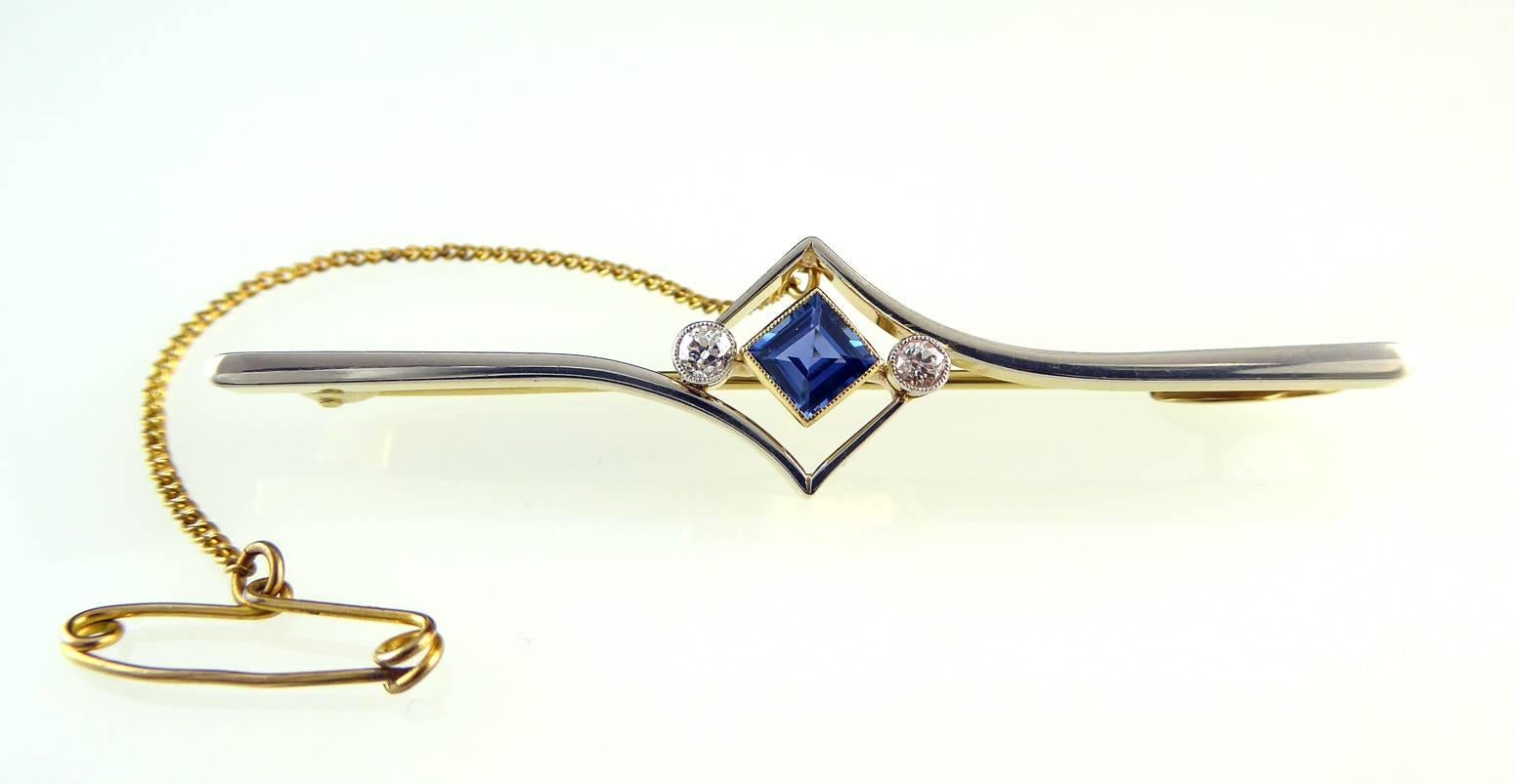A lovely Art Deco brooch set with a square cut sapphire placed on a point to the centre and partnered on each side by an old cut diamond.  This very elegant trio of gemstones sits within an open diamond shaped design in a typical 1920's style.  The