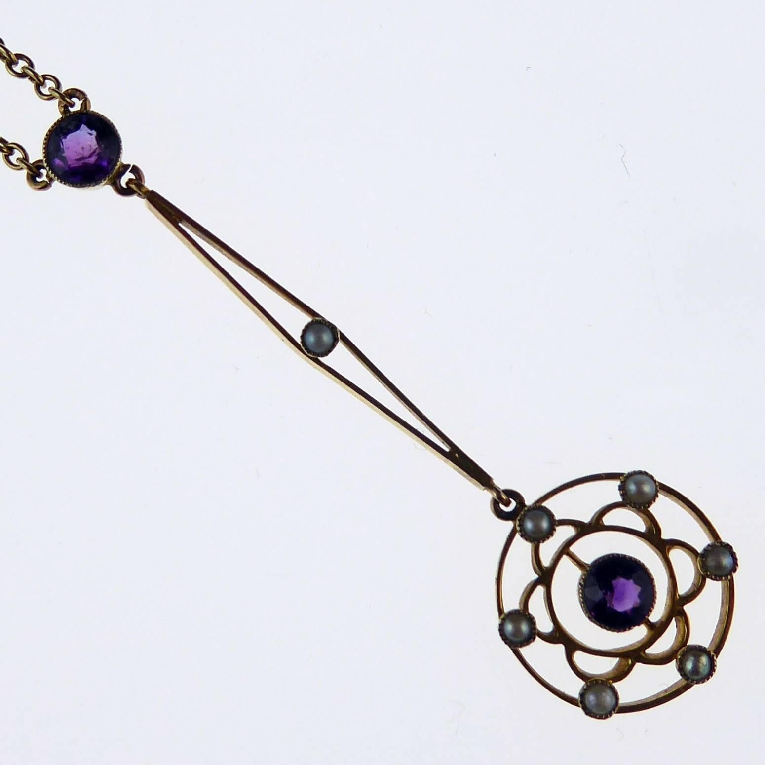 Edwardian antique pendant in an elegant and refined style.  
A round mixed cut amethyst is centrally set in grain setting in a gold circle bordered by six semi-circles, each semi-circle punctuated by a white pearl in millegrain edged settings. 