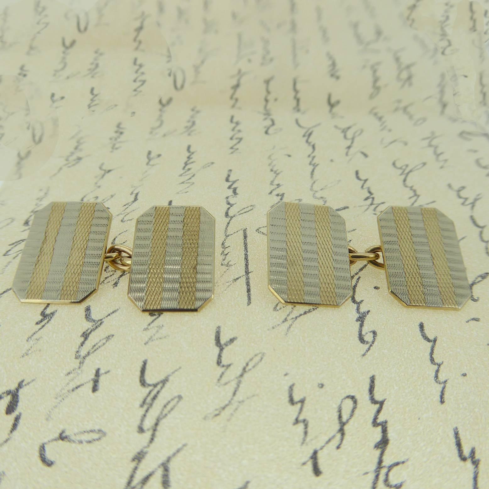 Vintage cufflinks dating from the 1960s in an Art Deco style, the shape being rectangular with cut corners.  The front of the cufflinks have a striped white and yellow machine engraved pattern and are connected by gold chain.  Stamped 9ct to the