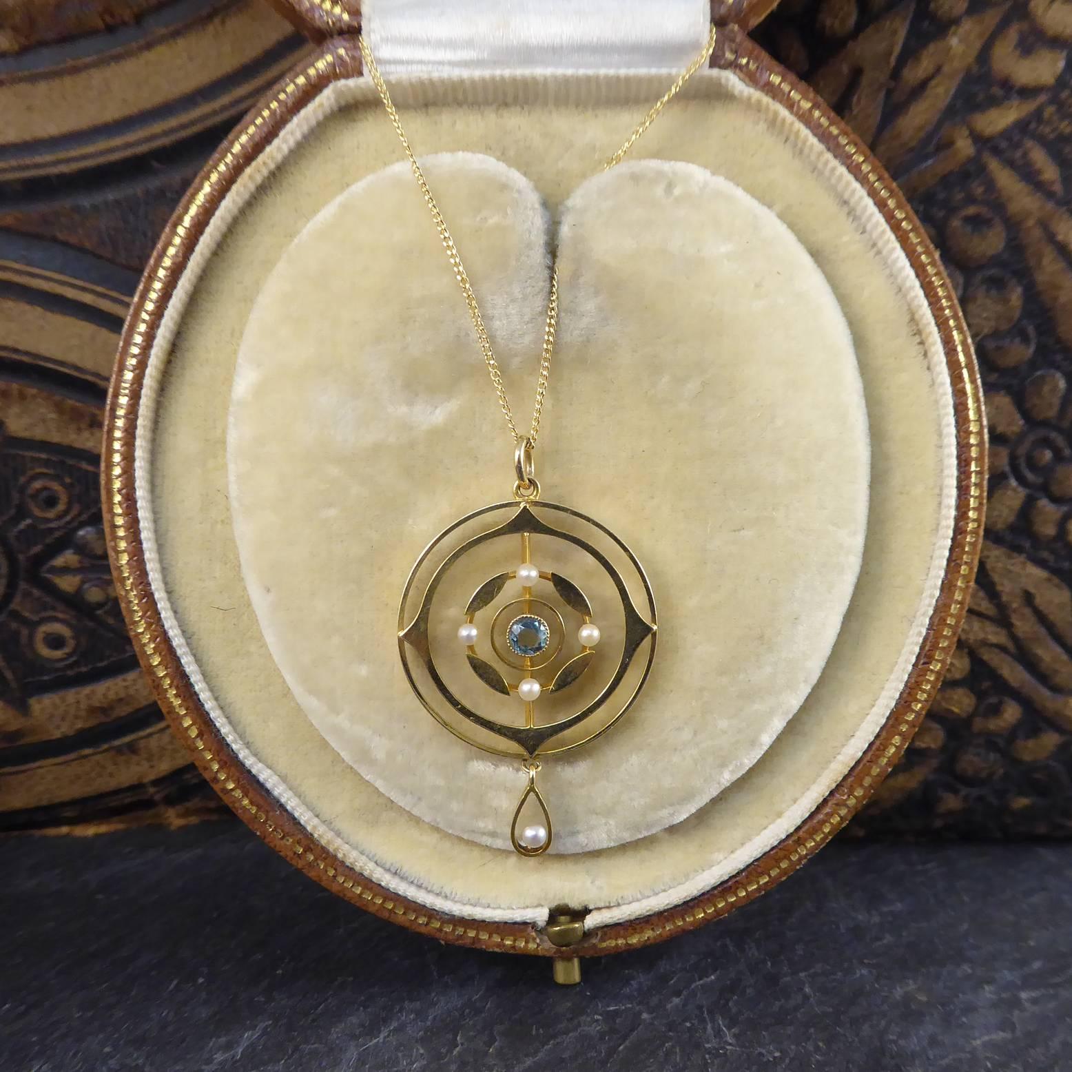 Created in the early Edwardian era this antique art nouveau pendant is set to the centre with a round aquamarine within a gold circle.  Four marquise shaped gold sections interspersed with a seed pearl enhance the aquamarine and the whole