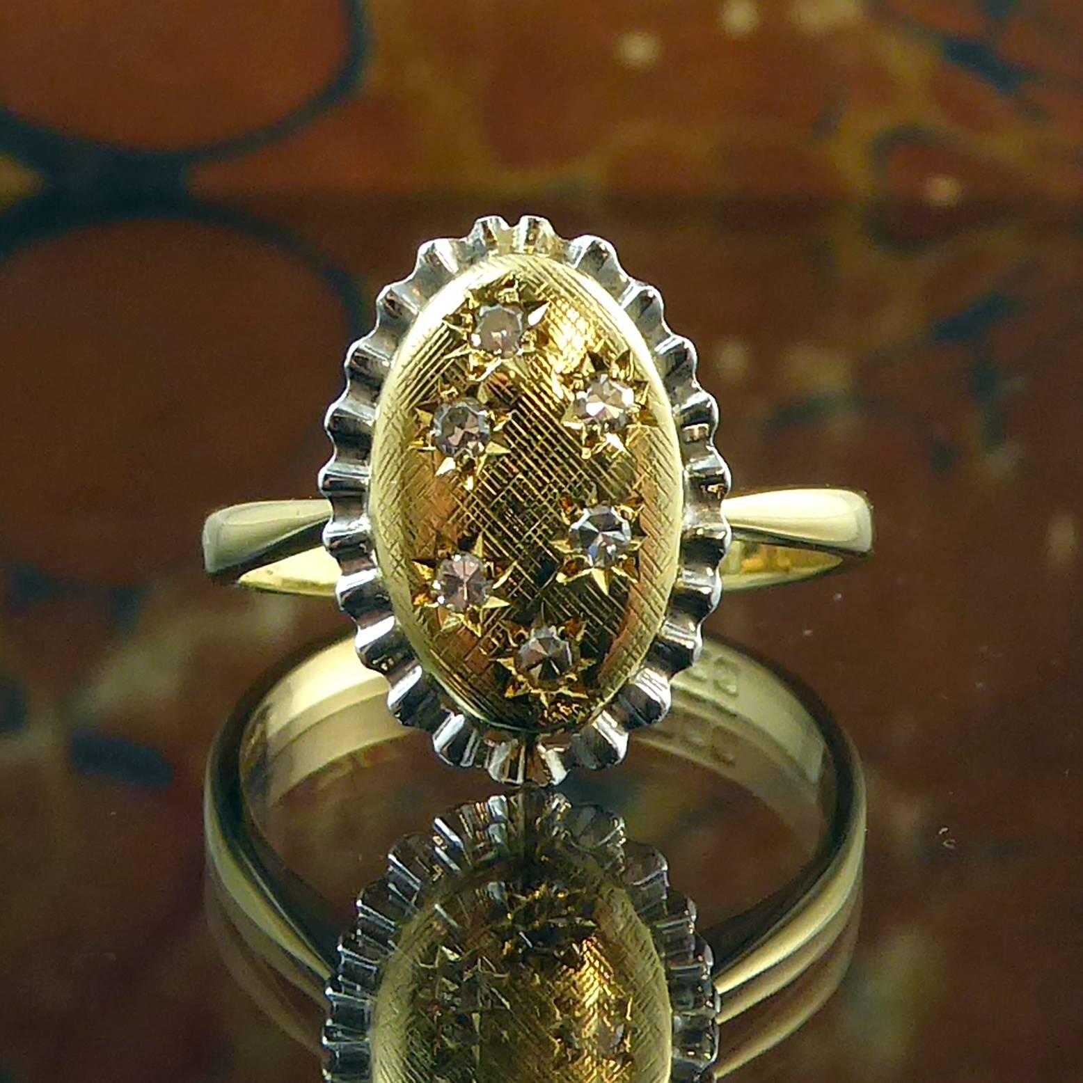 Designed in the 1980s, this is a fabulously pretty ring featuring a yellow gold oval studded with sparkling brilliant cut diamonds scattered around the top of the ring in star cut settings.  

The oval backdrop to the diamonds has a cross-hatch