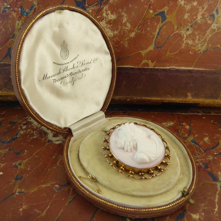 An antique Victorian cameo depicting an attractive classical female profile executed by a talented artist using the pink and white parts of the shell.  The woman has been shown wearing a very intricate hairstyle in which there appears to be sheaves
