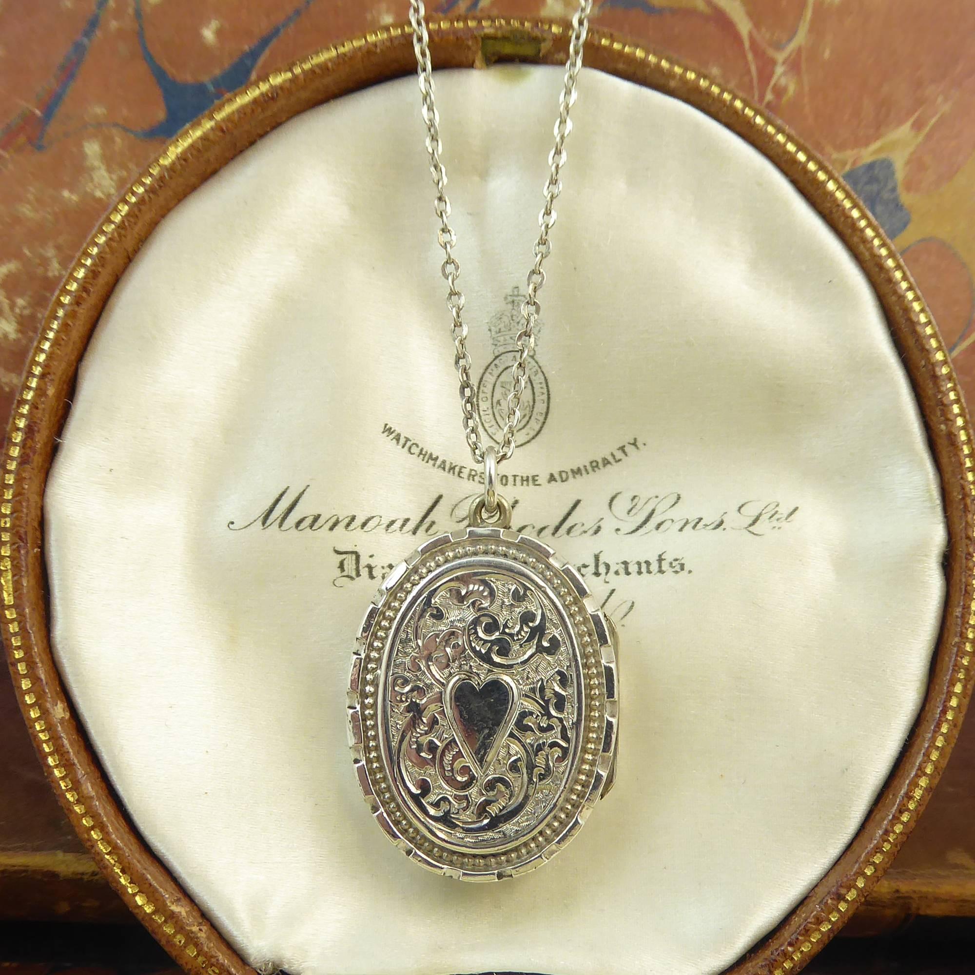 A really cute antique silver locket of very wearable proportions.  Dating from the later part of the Edwardian era, the locket  is very ornately hand engraved to the front with a raised oval border patterned with ancanthus leaf engraving in the