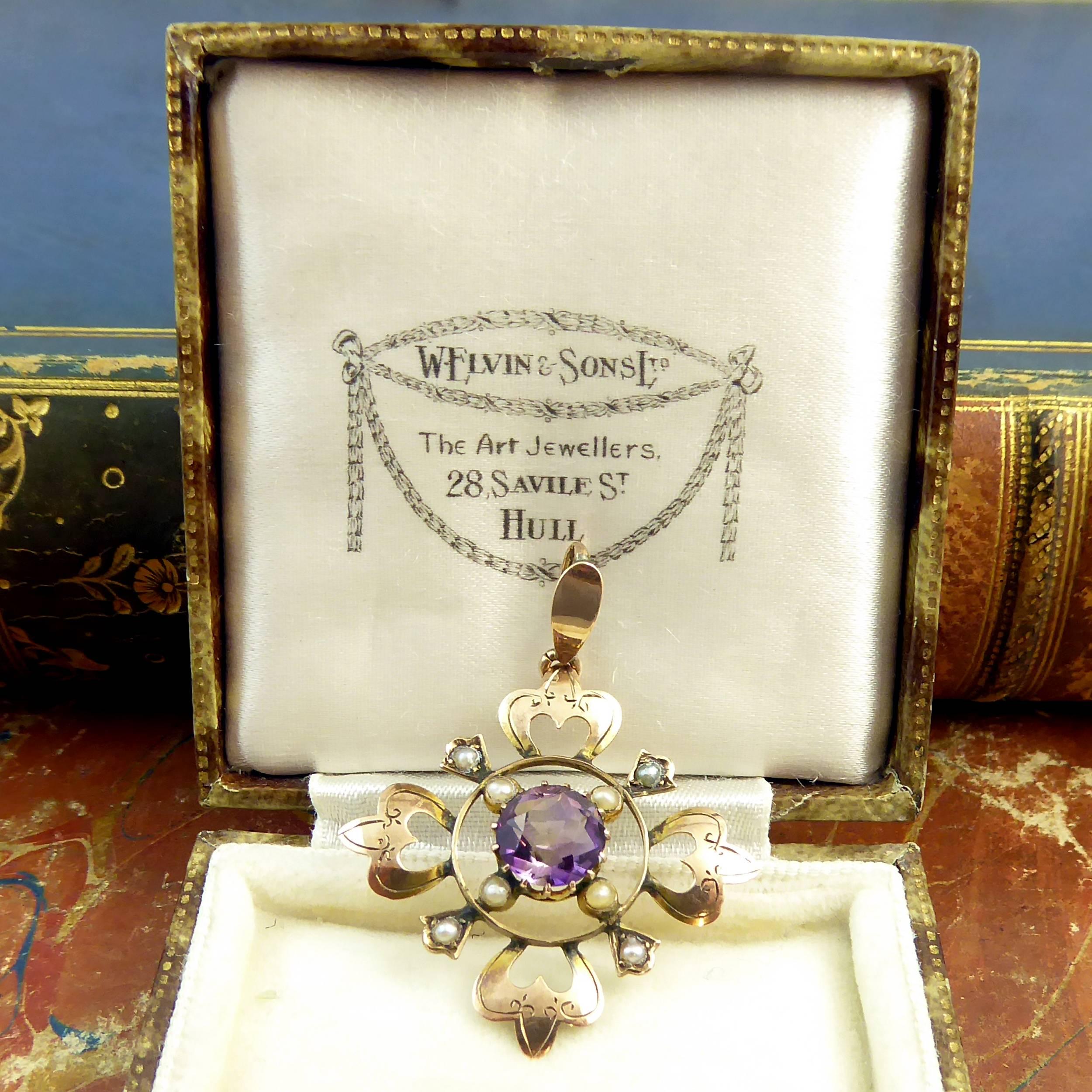 Antique pendant from the late Victorian era centrally set with a round mixed cut amethyst of good strong colour in a claw mount to a pearl and open wire surround.  The outer border of the pendant features four rose gold fleur-de-lys type decorations