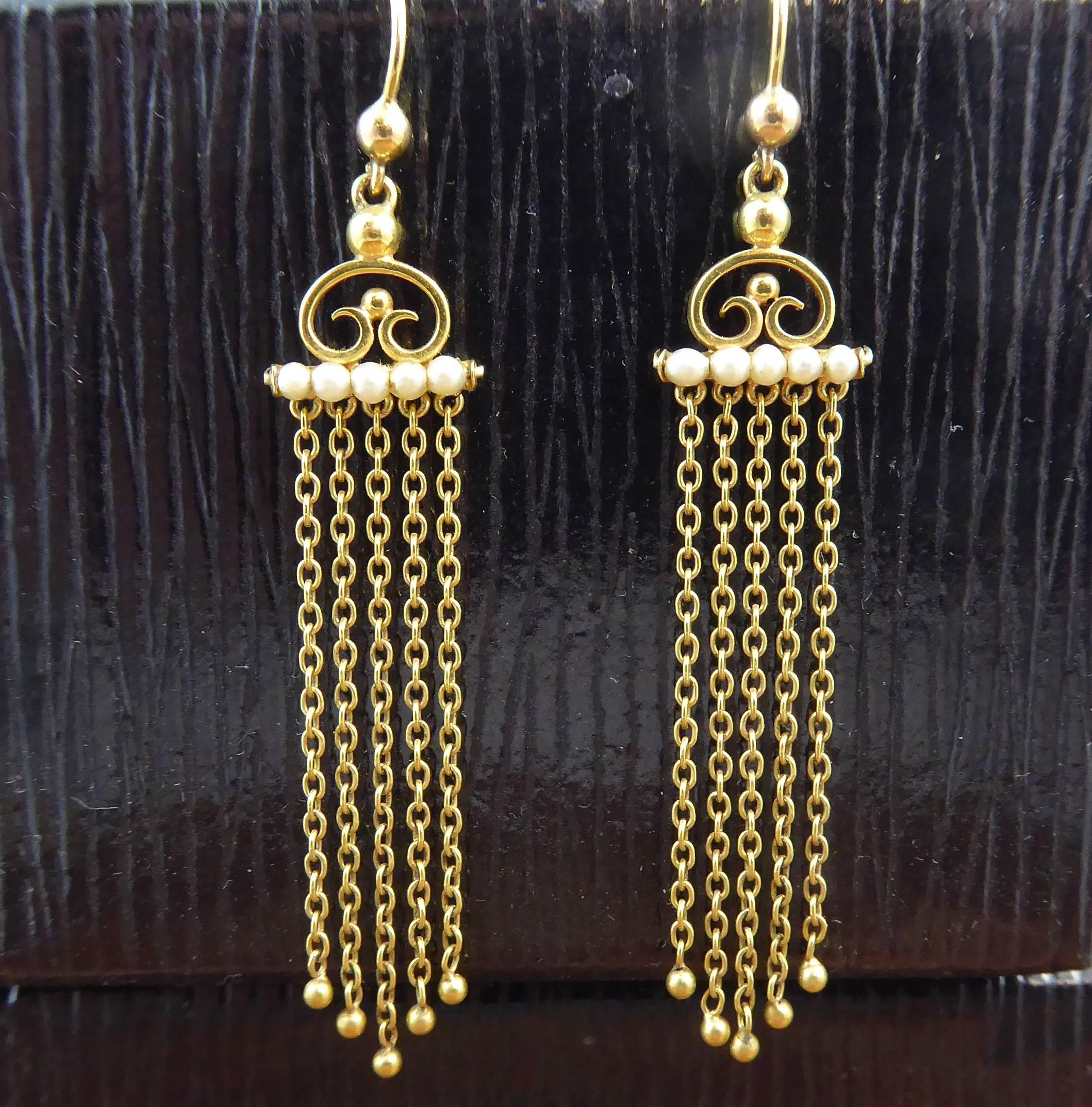 Delicious gold earrings from the Edwardian era, circa 1900. Set to the top with a C-scroll mount to a row of five pearls from which suspend five gold chains of varying lengths to product a V shaped fringe, each fringe terminating with a gold bead. 