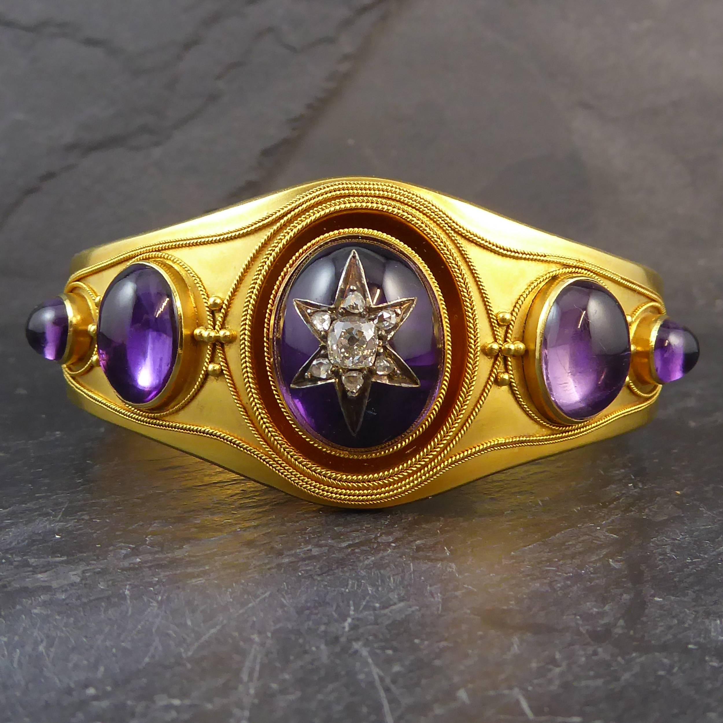 A Victorian five stone amethyst and diamond set hinged bangle of impressive proportions and design.  In the Etruscan style, the bangle comprises a shaped front, approx. 1.18 inches maximum width, containing five oval cabochon cut amethysts of