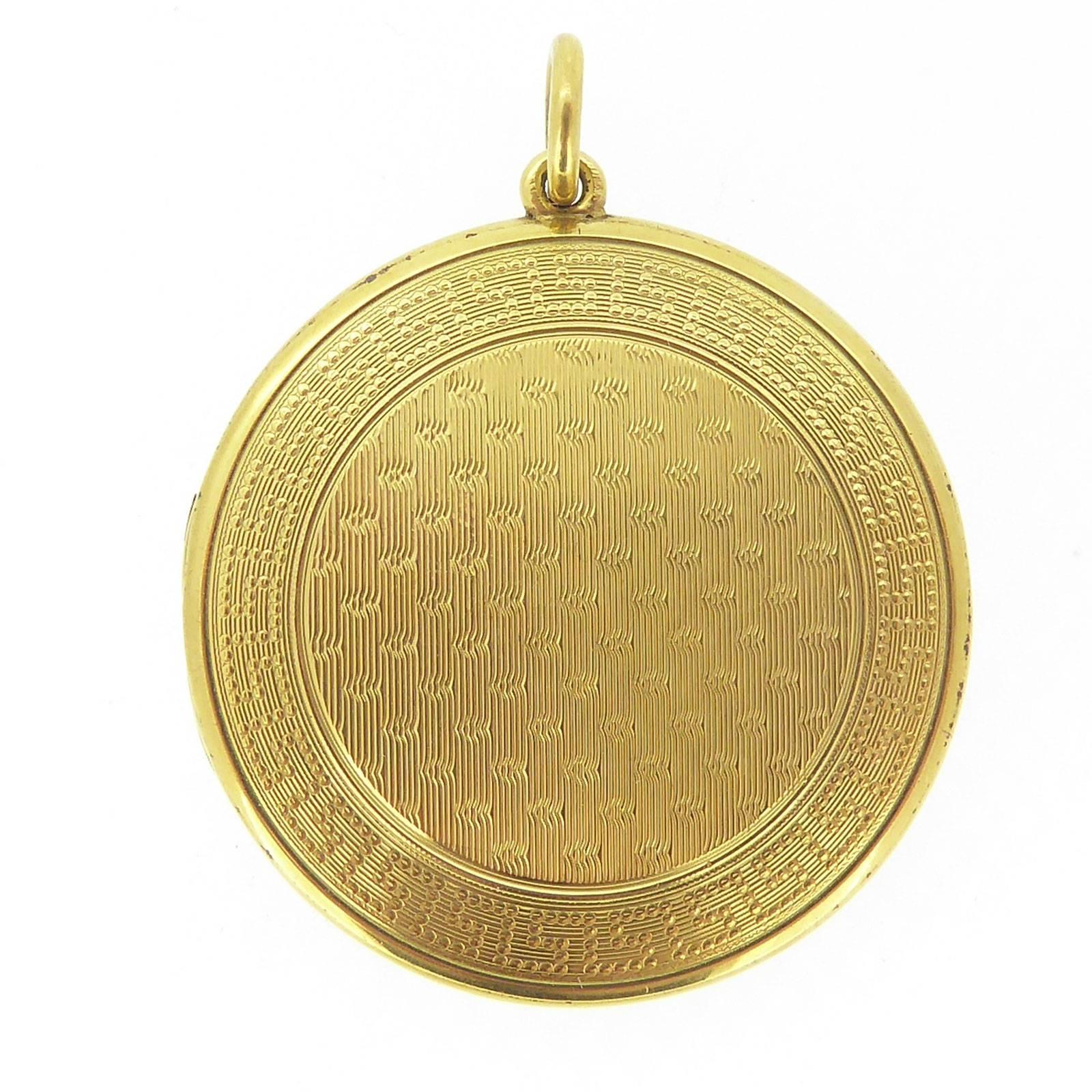 A beautiful Edwardian picture locket in yellow gold.  With a very tactile quality the locket is machine engraved to both sides with a central reeded pattern within a Grecian keylock border.  Additionally, the front of the locket has a plain polished