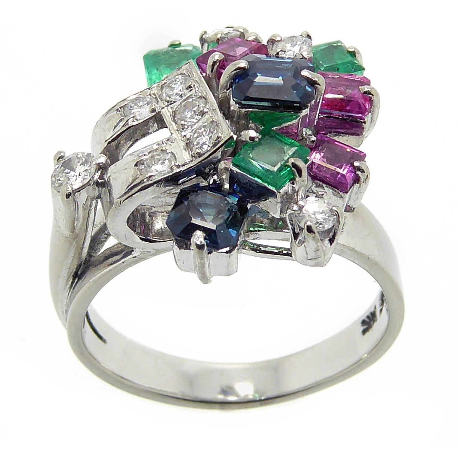 A fabulous confection of emerald cut dark blue sapphires, square trap cut rubies and brilliant cut diamonds in an asymmetrical cluster to a wide, 14k white gold band.  A stunning and unusual cocktail or right hand ring with must-have retro