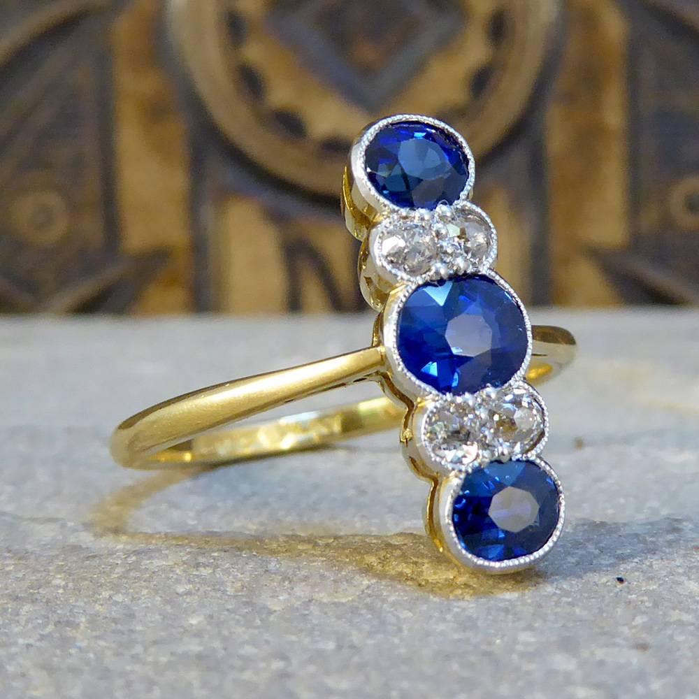 This stunning seven stone ring was crafted in the Edwardian era in 18ct yellow gold and platinum. Featuring three brilliant blue sapphires surrounding four small diamonds, the stones sit vertically on the finger.

Eye-catchingly striking, this piece