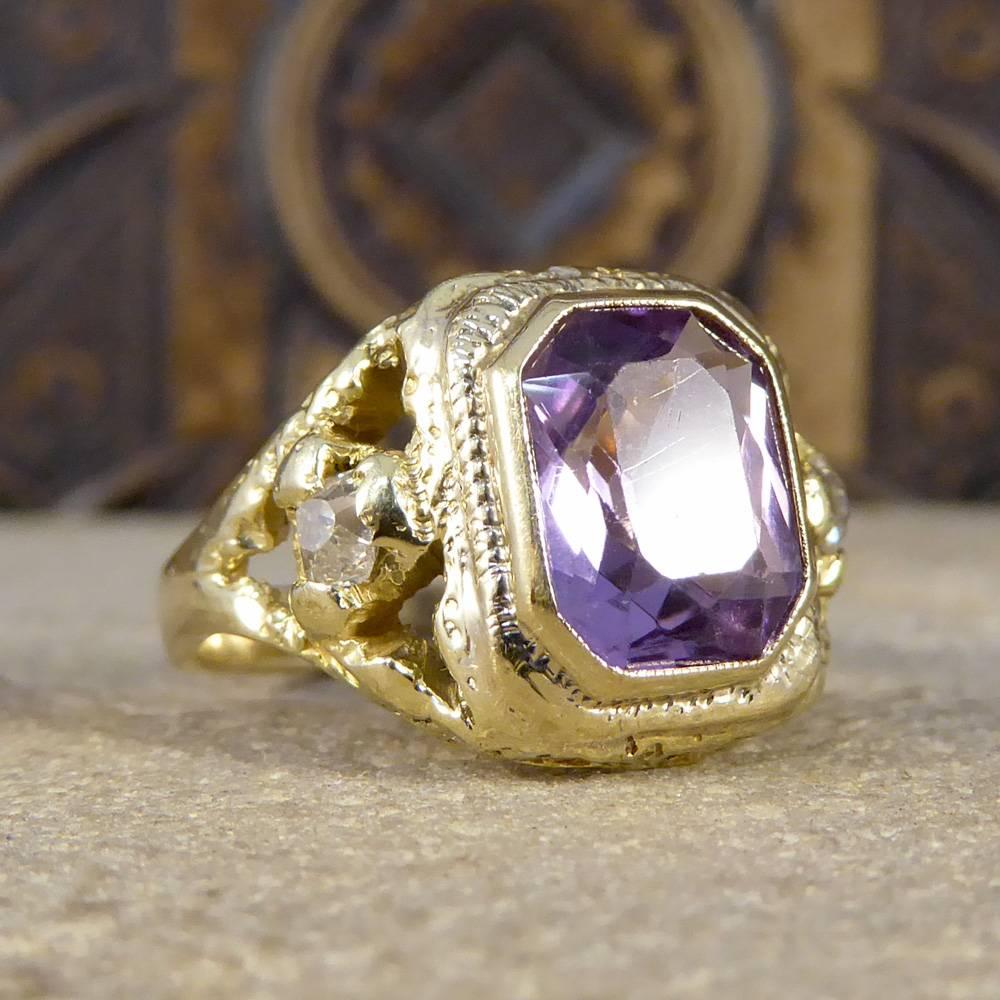 This Early Victorian ring features a single Amethyst stone with a rub over collar setting with a faded millegrain edge decoration. At either side of the Amethyst there is a triangle pattern with a Old-Cut Diamond centre and intricate detail showing