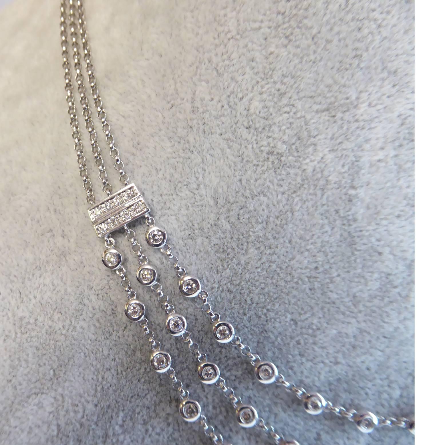 A modern, diamond necklace of recent vintage comprising three strands of rub-over set diamonds (40 diamonds in total), suspended by chain from two rectangular white panels each grain set with two rows of four brilliant cut diamonds.  These panels