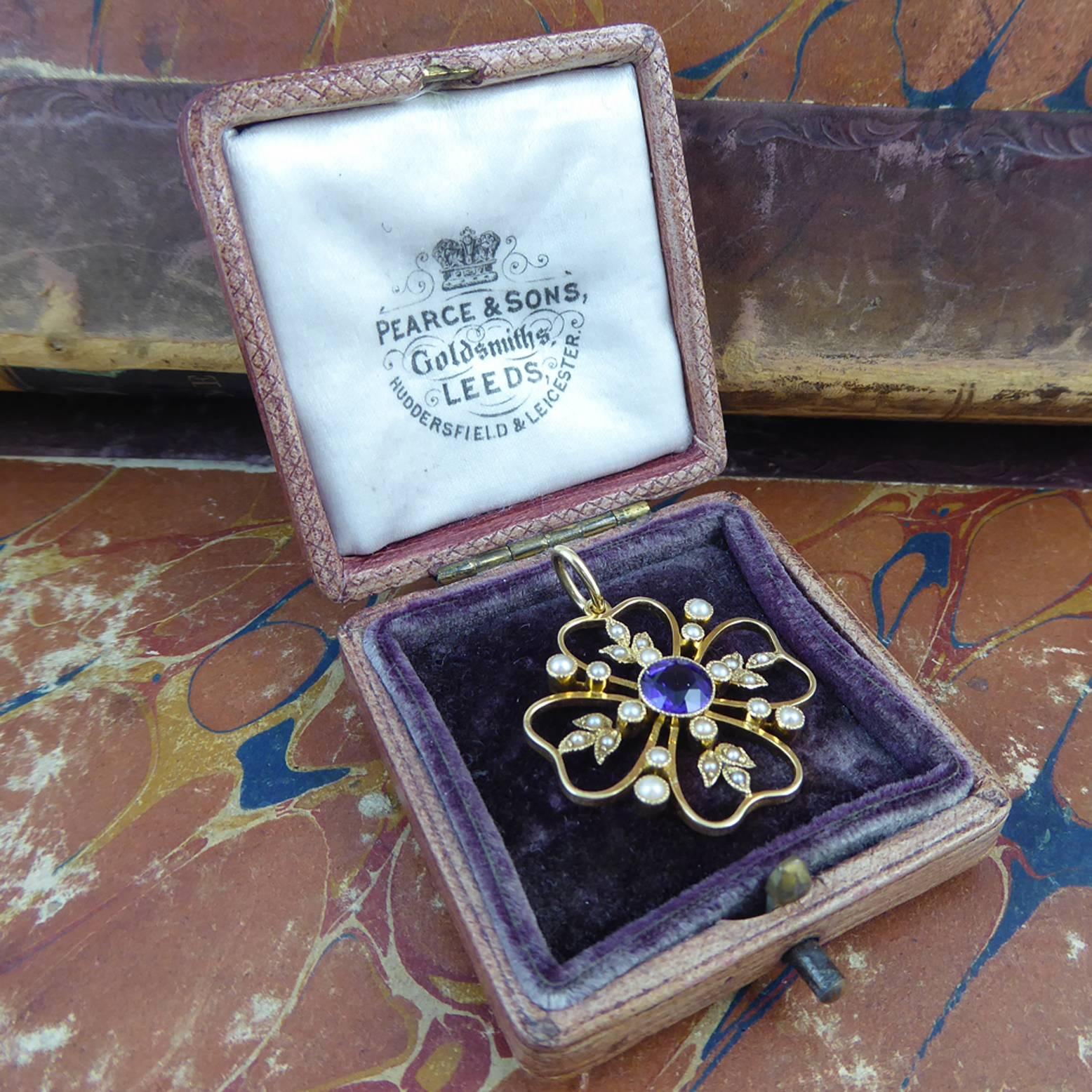 An antique pendant created in the early Edwardian era having an exquisitely coloured amethyst to the centre of a pearl set spray .  Four open wirework heart shaped sections encircle the amethyst and the inside of each heart features a delicate