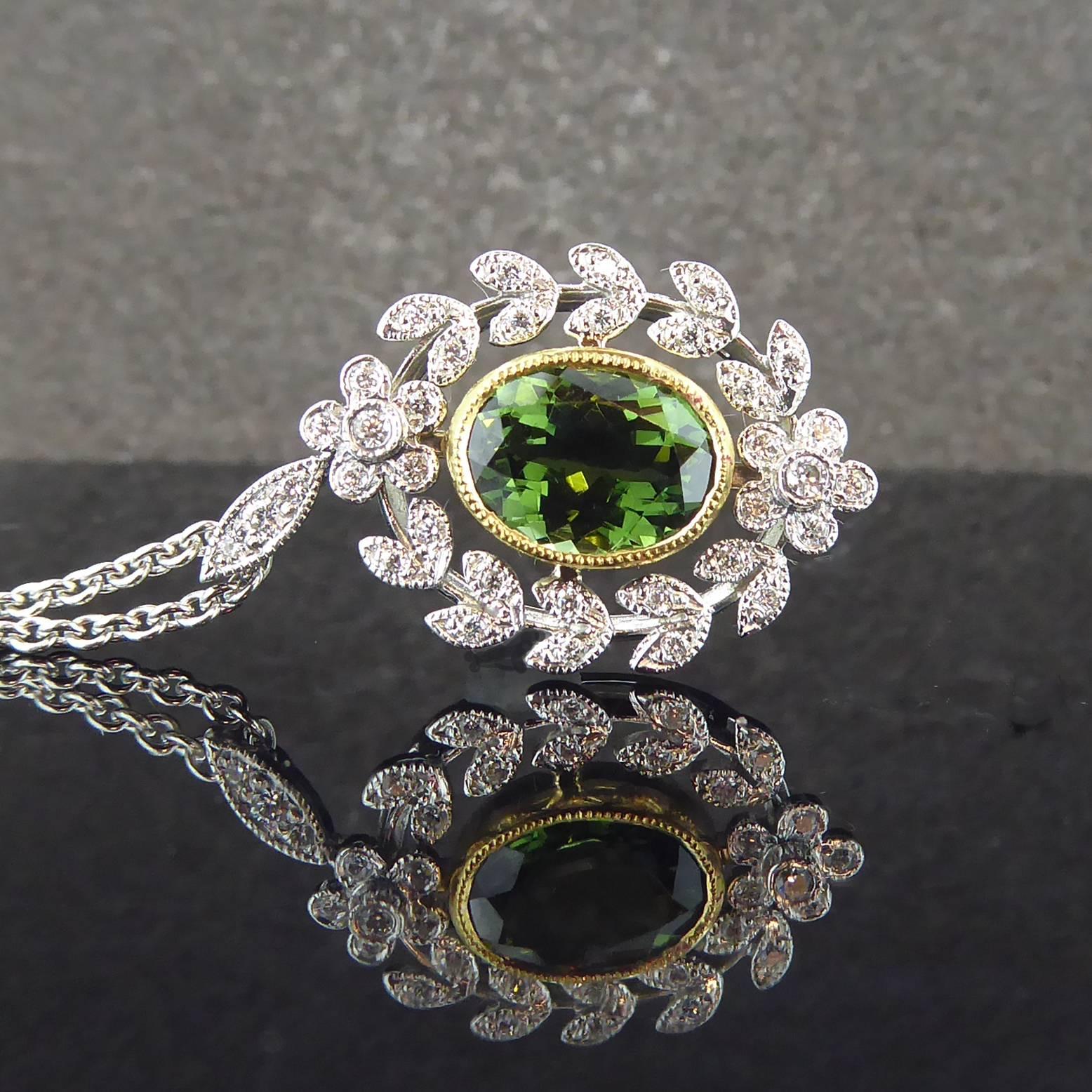 A refined an elegant antique style pendant created in the Belle Epoque style which lasted from the 1870s through to the outbreak of the 1st World War.  Set to the centre with an oval, mixed cut green tourmaline of deep and rich hue in a contrasting