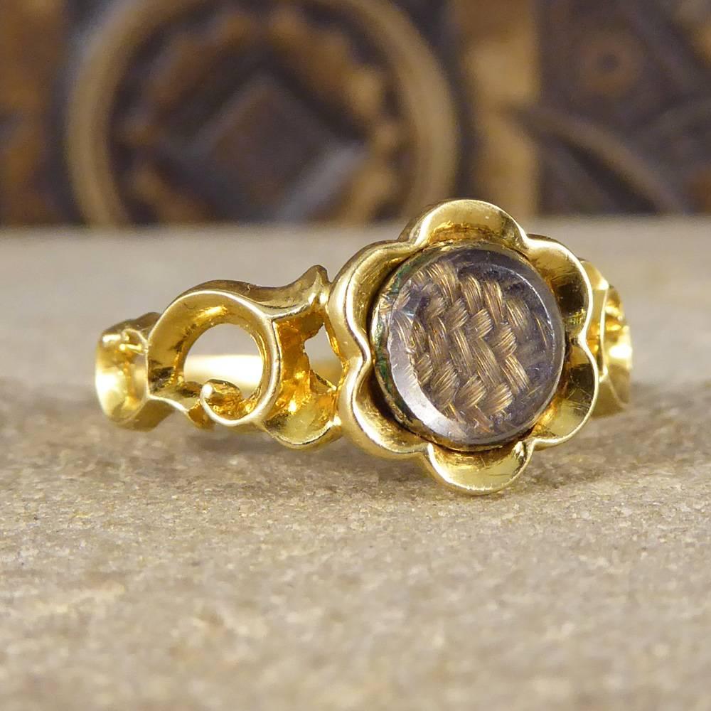 This pretty antique ring has been crafted in the Early Victorian era. Featuring a small circle panel with platted hair surrounded in a flower 15ct yellow gold setting and band, it sits classically on the finger.
Mourning jewellery helps celebrate