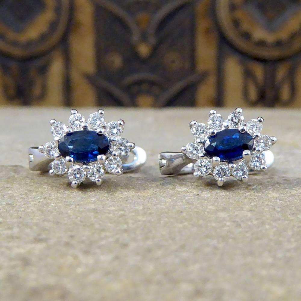 These gorgeous cluster earrings each feature an 0.20ct oval cut sapphire stone surrounded by ten delightful diamonds.
Modeled in 18ct white gold with secure lever backs, they look very alluring on the ear!

Condition: Very Good, slightest signs of