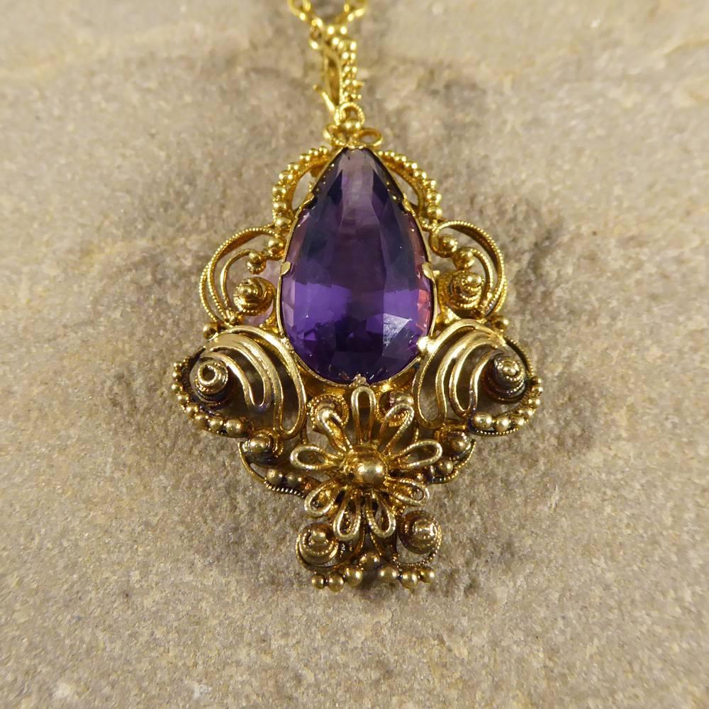 This vintage necklace features a single pear shaped Amethyst held into place with a secure 8 claw setting. Surrounded by beautifully decorated with 15ct Yellow Gold curled and formed into different shapes with an etruscan detailing. This pendant is