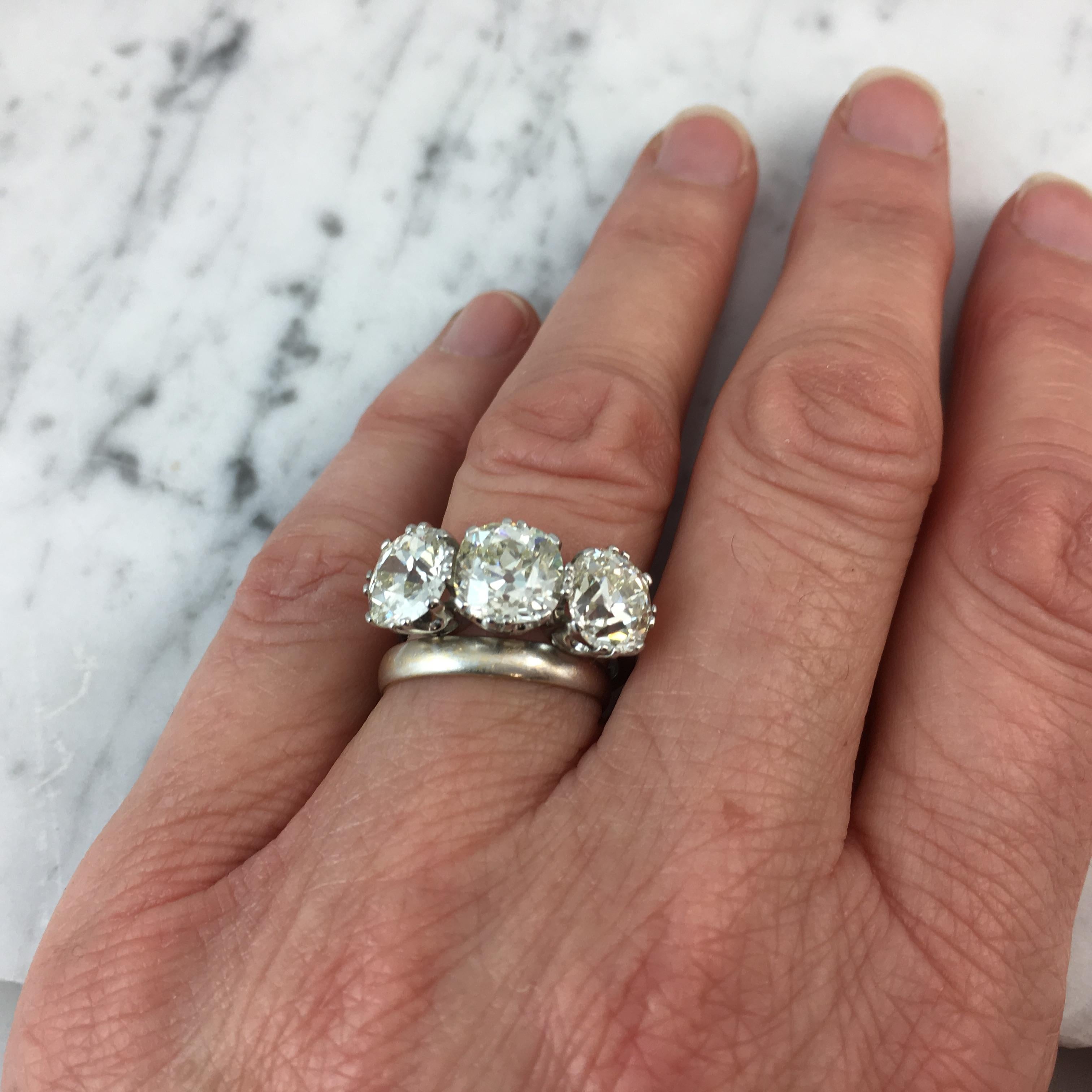 A spectacular three stone diamond ring set with three cushion shaped old European cut diamonds with weighed carat weights of 2.27ct, 2.72ct and 2.40ct.  The colour ranges from approximately N to tinted with clarity from VS1 to SI giving a lovely