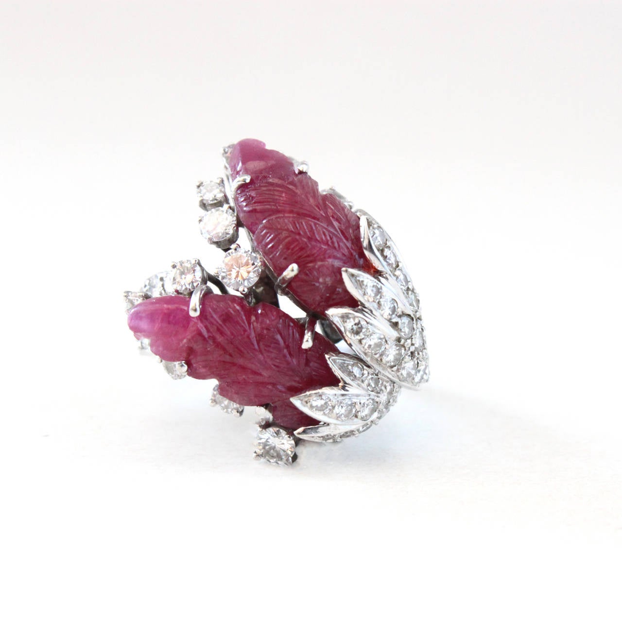 A carved rubies and diamond white gold ring, beautifully designed in the form of swan feathers. The carved rubies are of Burmese origin and form the end of two feathers. They are surrounded by ca. 2-3 carats of round brilliant diamonds (quality