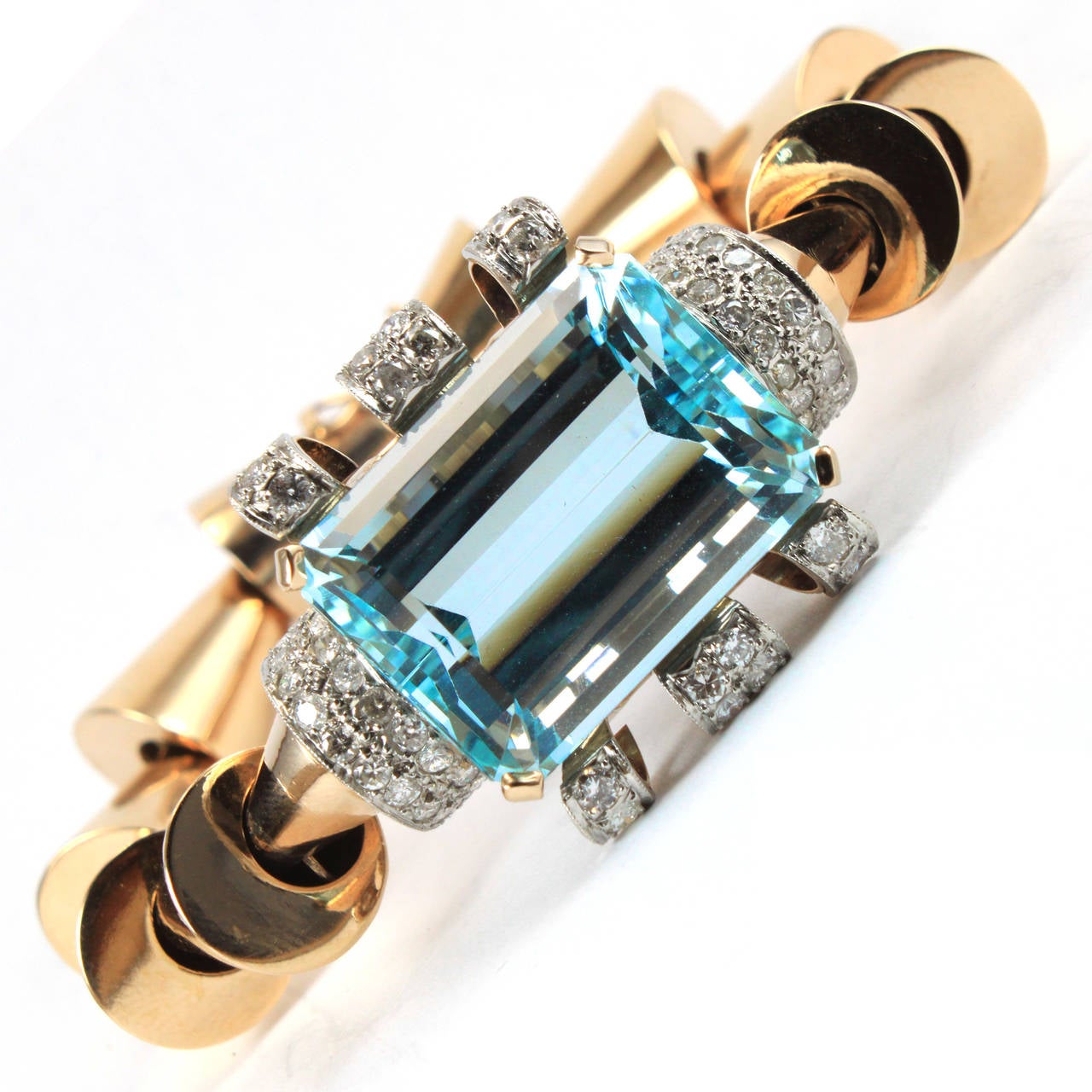 A very chic and unusual 1940s bracelet. It is made out of beautiful 18k gold links showing a classic retro feature of the starting of the machine age. The gold links lead to a beautiful Aquamarine of circa 50 carats, which is surrounded by diamonds