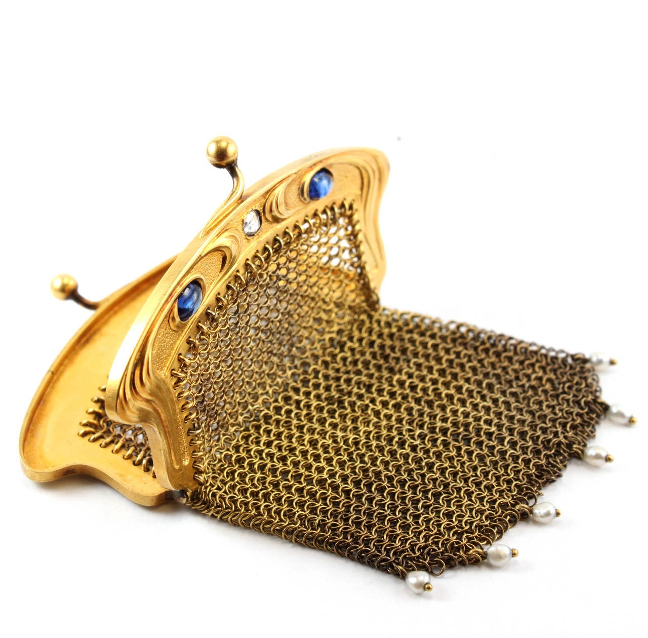 An Art Nouveau gold mesh bag, 1900, with two sapphire cabochons, a rosecut diamond and hanging seed pearls. The gold mesh is beautifully interlinked and in an excellent condition. The gold bag has Dutch hallmarks and is in 15k yellow gold.